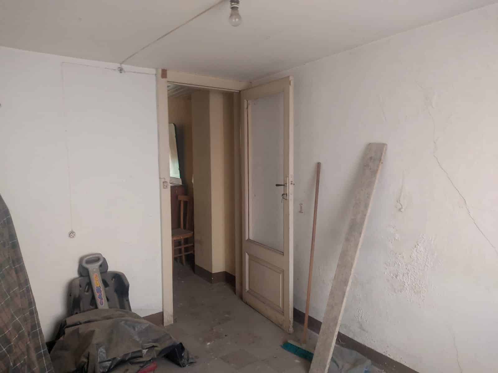 Finestra in ristrutturazione con pareti incompiute, attrezzi da lavoro e materiali edilizi in una stanza in fase di rinnovo immobiliare.