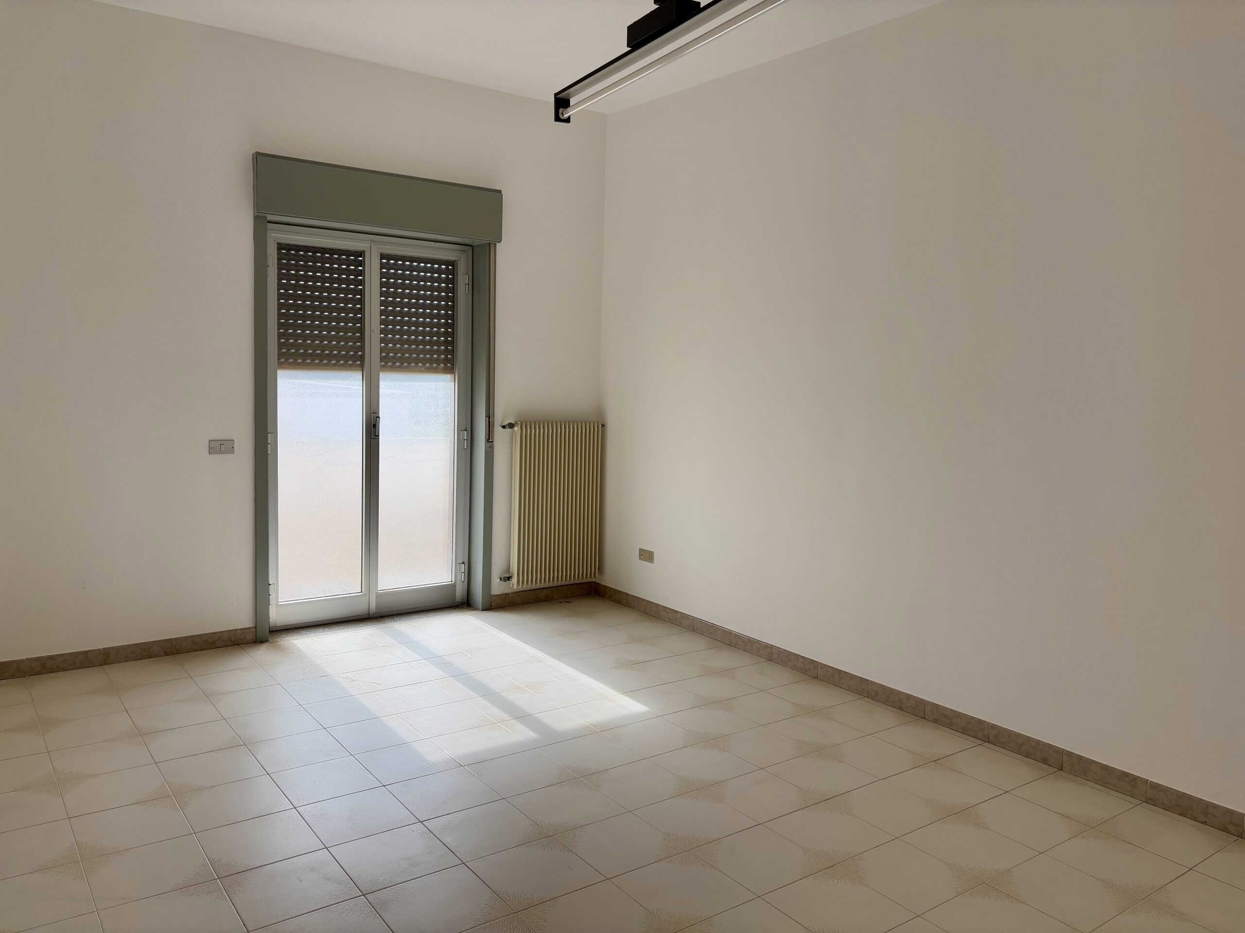 Finestra con porta finestra e tapparella in una stanza vuota, luminosità naturale, aria condizionata, ideale per arredare casa, immobile in vendita o affitto, NextCasa.