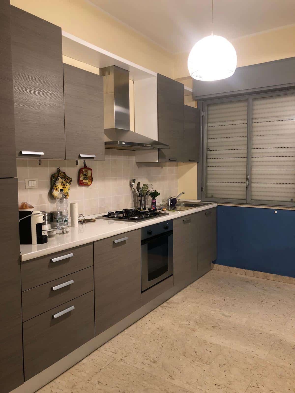 Cucina moderna con mobili in gres effetto legno, piano di lavoro in marmo e dettagli eleganti, ideale per ambienti di casa eleganti e funzionali.