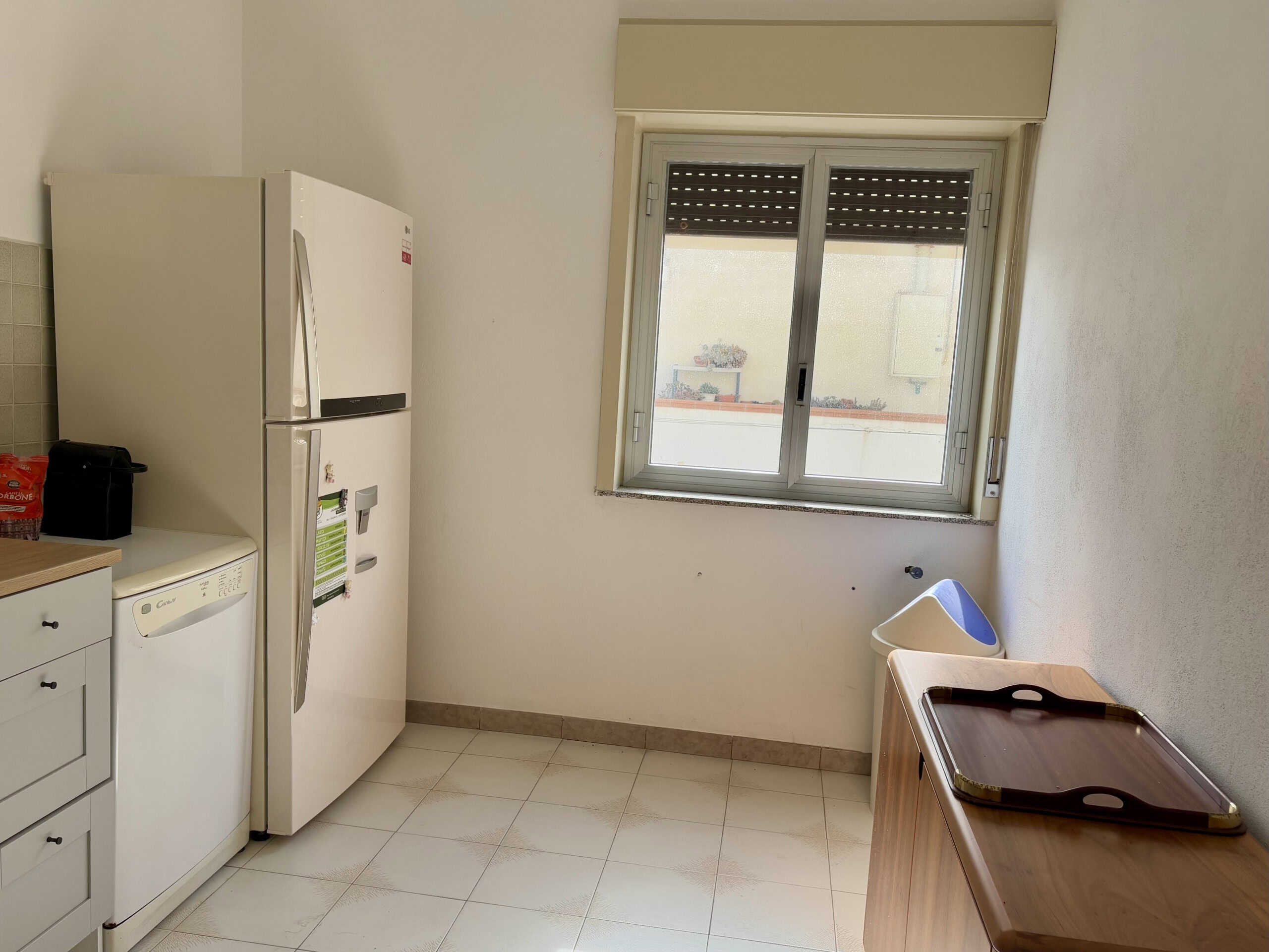 Lavatrice e frigorifero in cucina con finestra, spazio funzionale, arredo semplice, ideale per appartamenti in vendita o affitto, soluzioni abitative moderne.