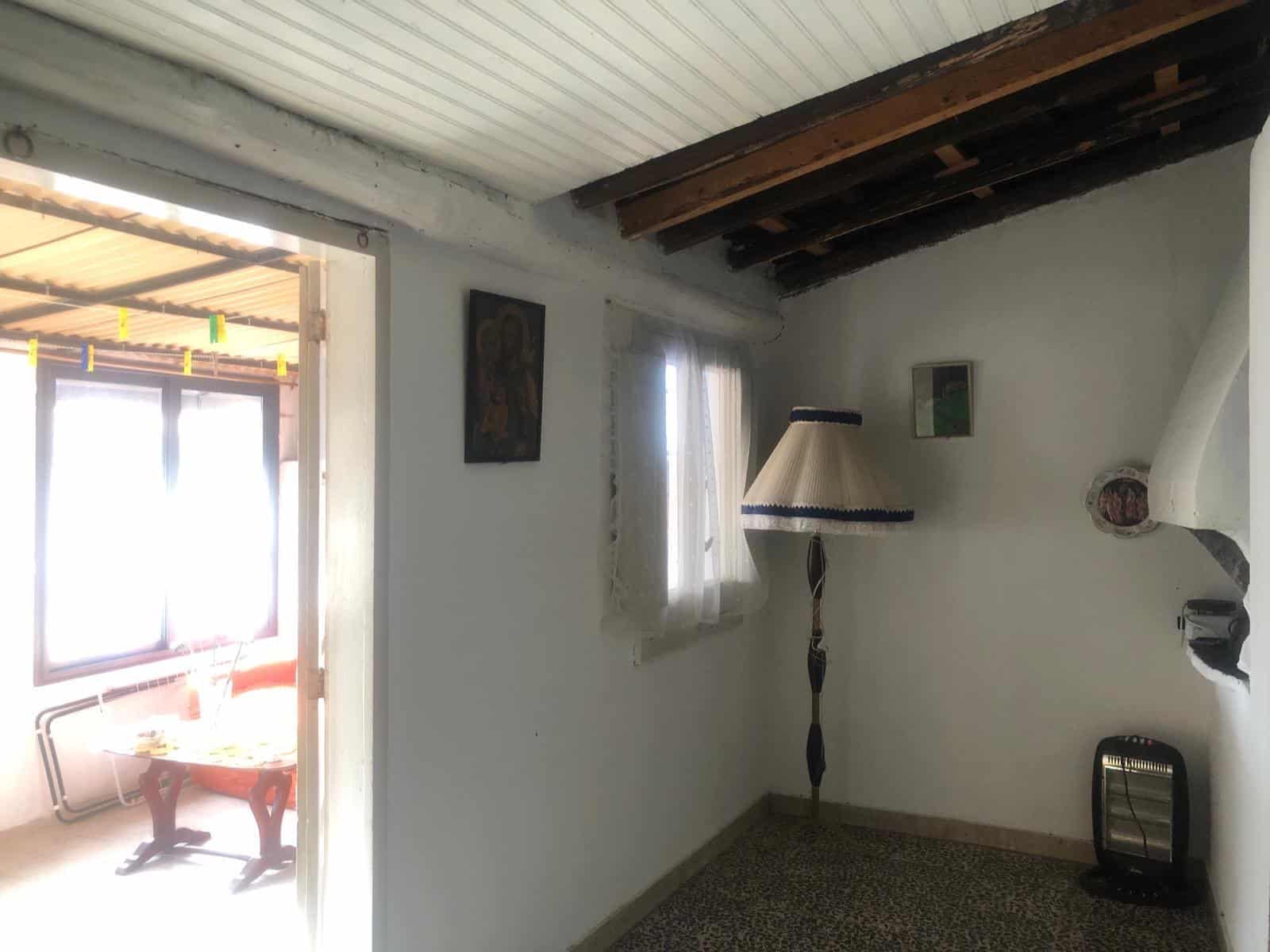 Vecchia casa in stile rustico con soffitto a doppia altezza, pareti bianche, soffitto con travi in legno e piccola finestra, ambiente accogliente e caratteristico, ideale per ristrutturazione e valorizzazione architettonica.