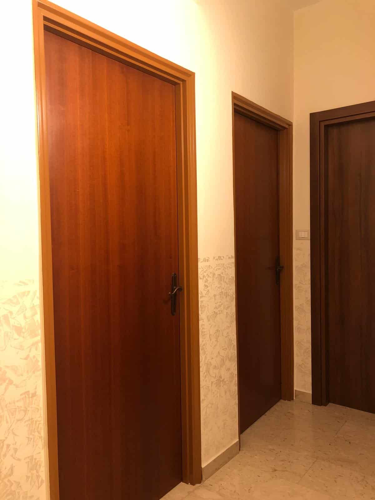 Porte in legno interne con finitura in noce scuro, in un ambiente moderno di proprietà residenziale e commerciale, perfette per ambienti eleganti e funzionali.