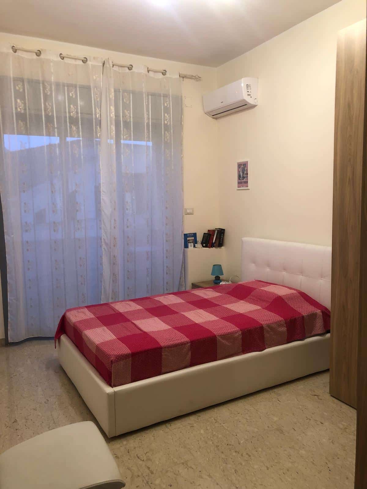 Letto-con-materasso-rosso-e-bianco-in-camera-da-letto-con-armadio-in-legno-e-lampada-blu.