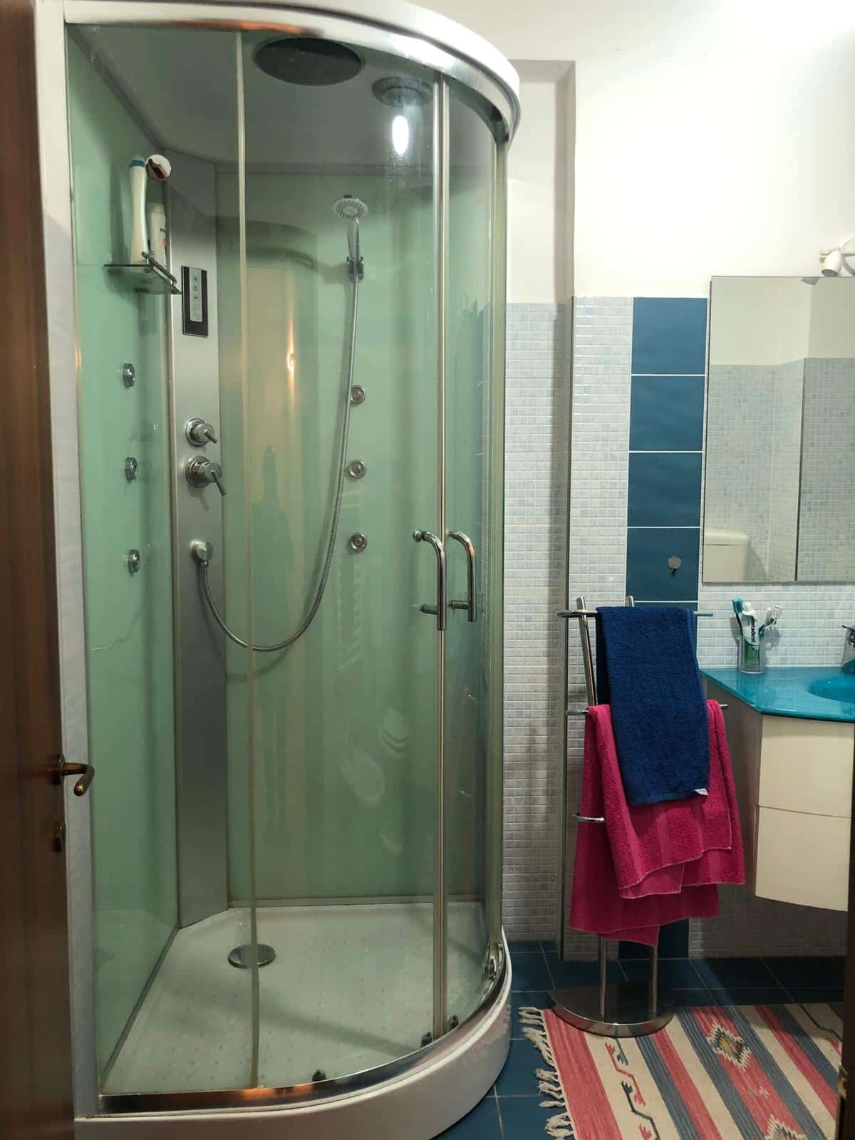 Vasca idromassaggio angolare con doccia nel bagno, dettagli moderni e funzionali, ideale per il massimo comfort domestico.