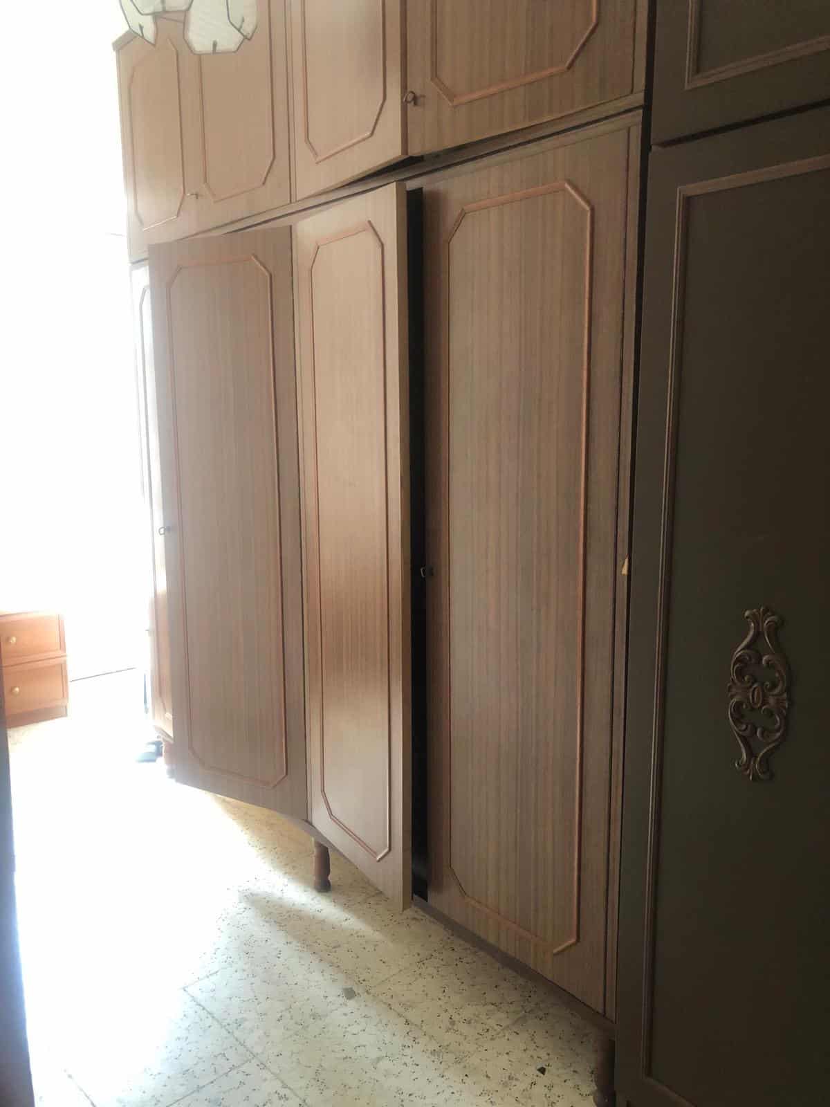 Armadio in legno massello con ante a battente, stile classico, con maniglie decorative e finiture eleganti, ideale per arredare camere da letto o soggiorni.