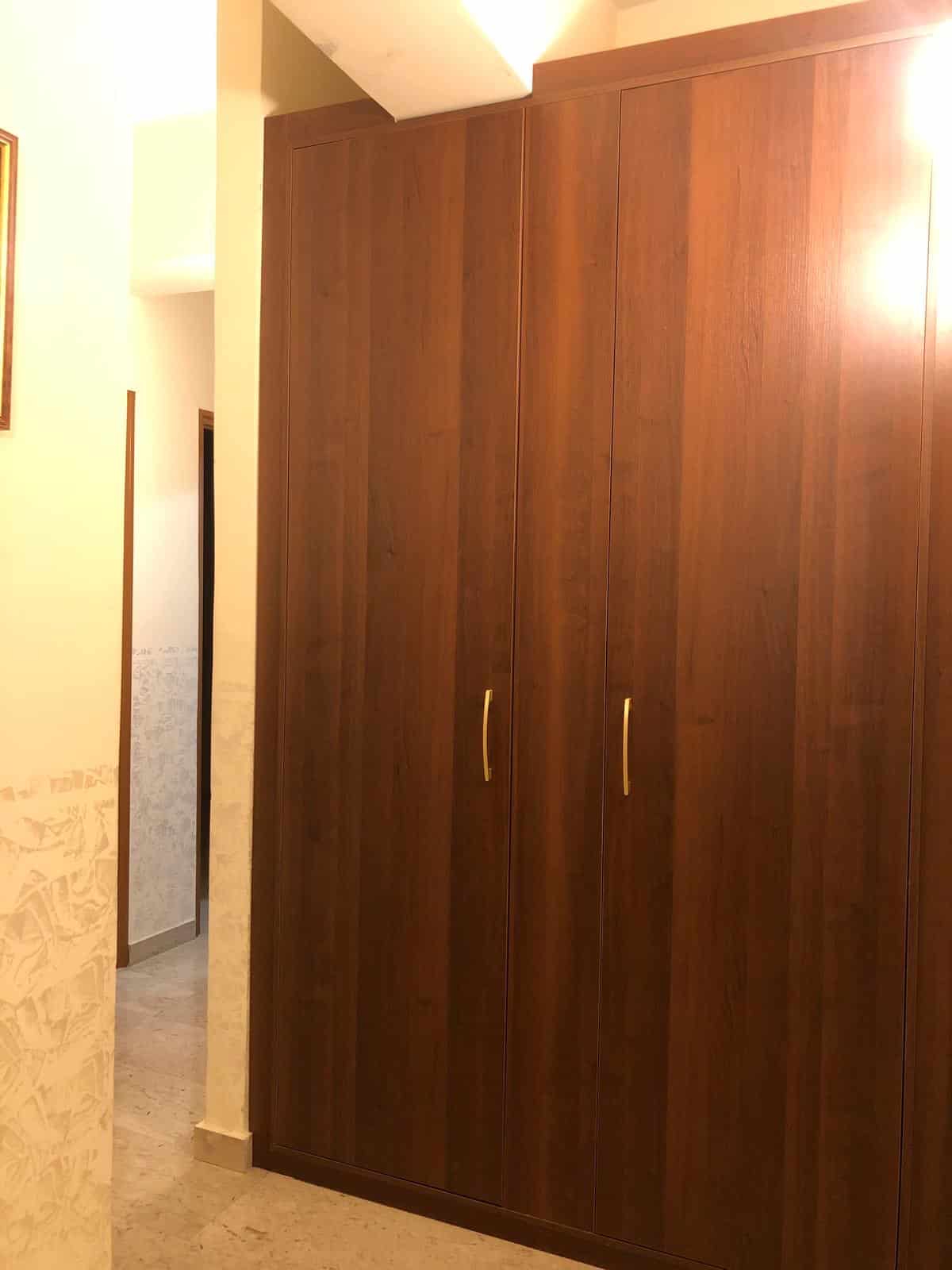 Armadio a tre ante in legno scuro, ideale per organizzare l'armadio in soggiorno o camera da letto, con maniglie in metallo dorato, arredo pratico e elegante.