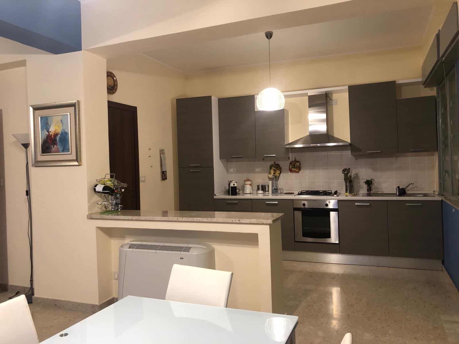 Elegante cucina moderna con mobili grigi, piano di lavoro in marmo e elettrodomestici in acciaio inox, ambiente accogliente e funzionale ideale per la vita quotidiana.