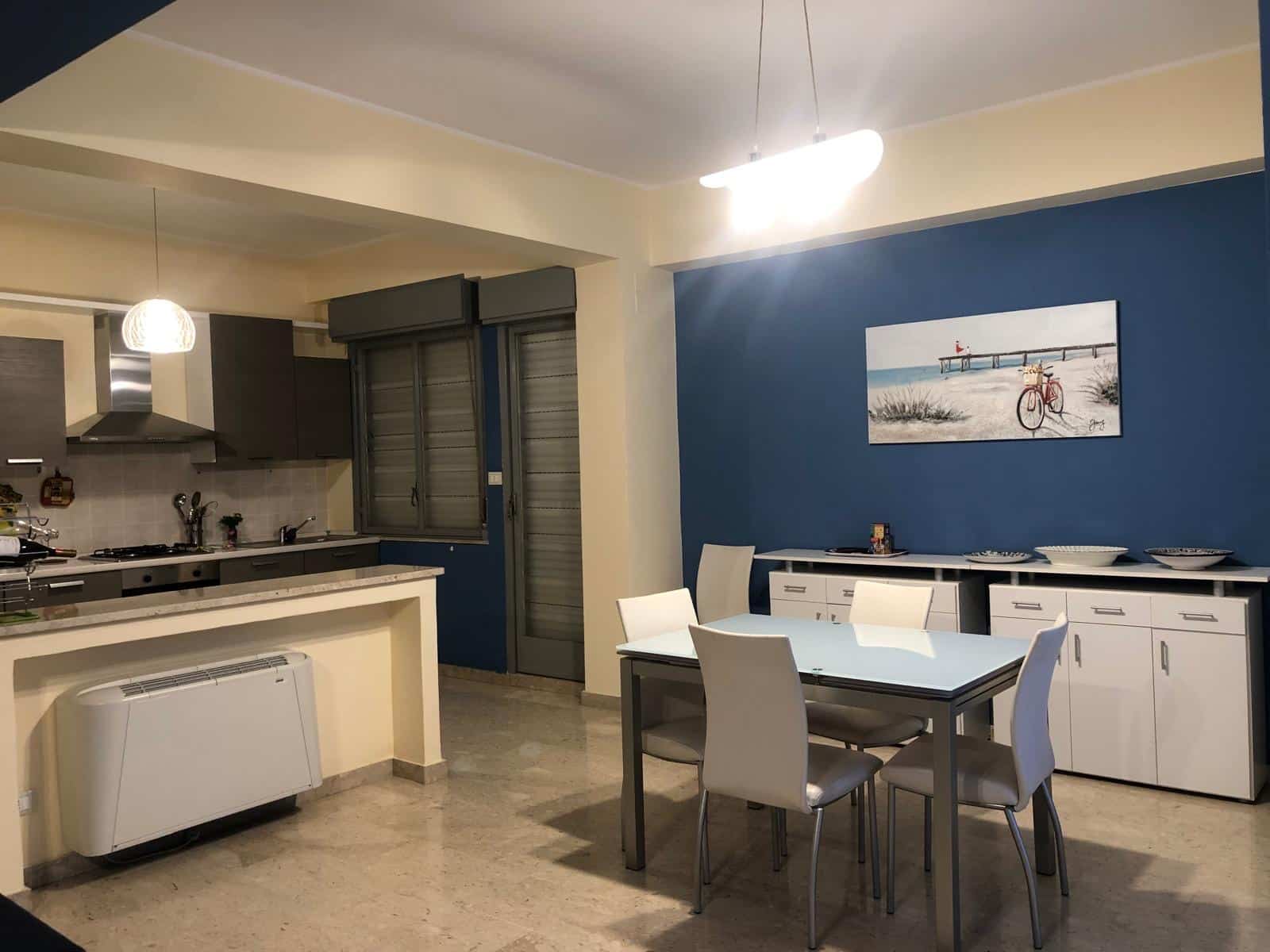 Spazio cucina e zona pranzo in appartamento con pareti blu e arredi moderni, ideale per vivere in comfort e stile. Perfetto per chi cerca soluzioni di arredamento eleganti e funzionali.