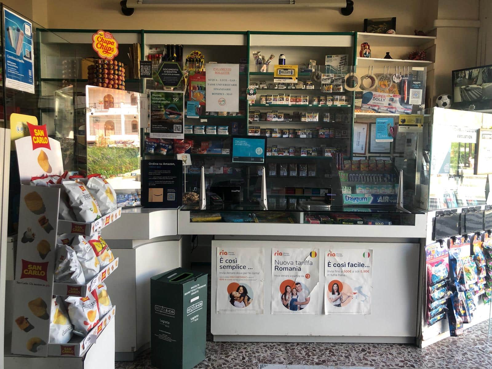 Terminale di vendita di generi di prima necessità e tabacchi in negozio NextCasa, con snack, sigarette, biglietti e servizi di pagamento. Ambiente colorato e ben organizzato, con prodotti ben visibili e aree dedicate alla clientela.