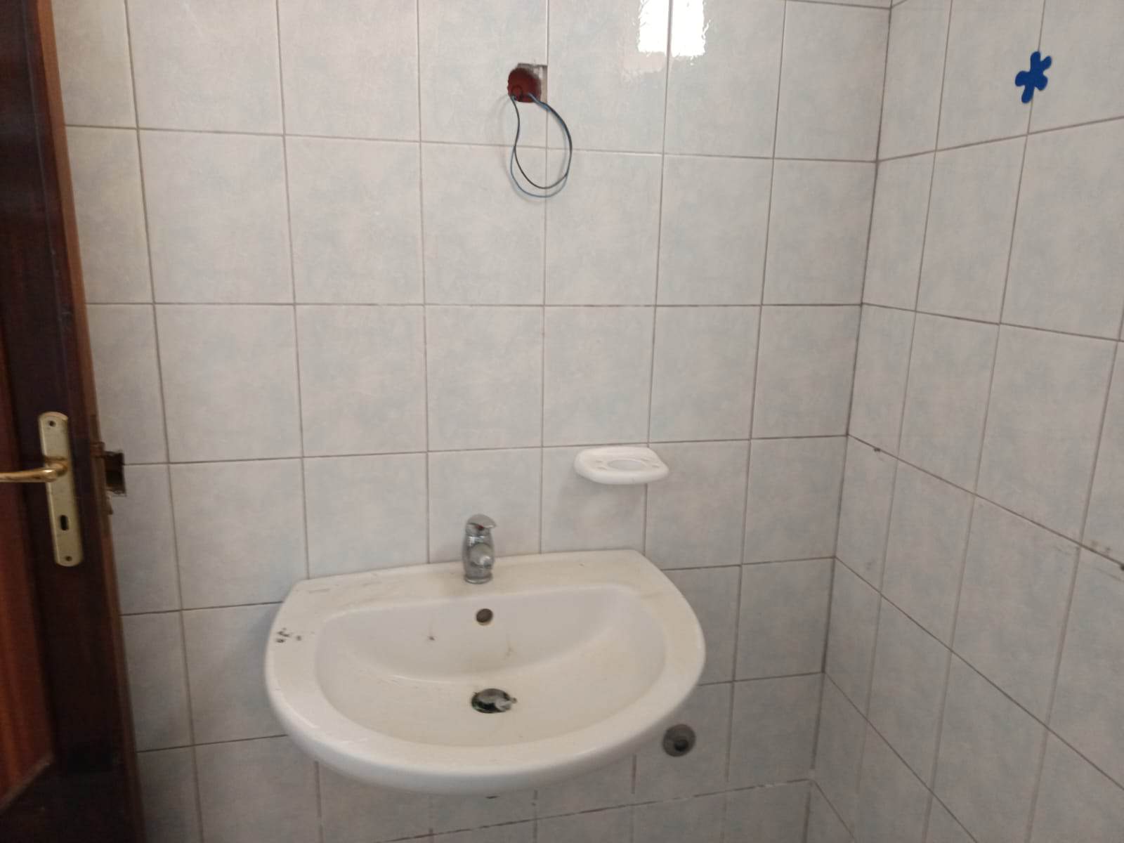 Lavabo bianco in bagno con piastrelle chiare, esposizione di lavori di ristrutturazione, pronto all'installazione di accessori e arredo; immagine di un ambiente in fase di completamento.