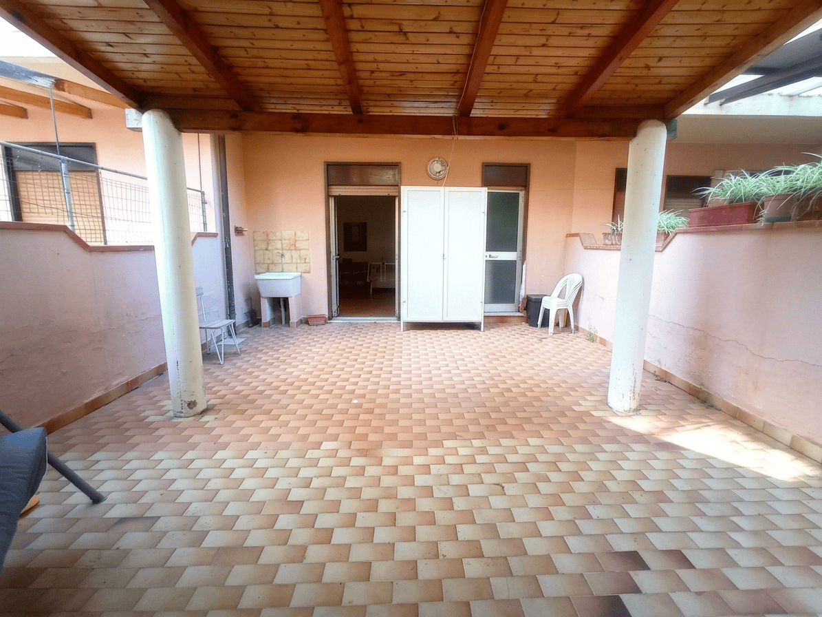 Ampia terrazza coperta con pavimentazione in piastrelle, vista su cortile e ingresso dell'appartamento in via Stazione 90, Oliveri, Me.