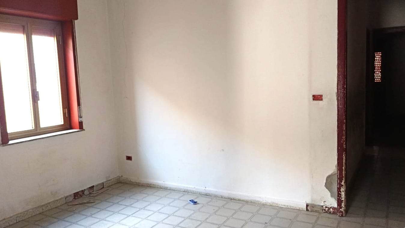 Rendering immobiliare in fase di ristrutturazione con pareti vuote e pavimento in ceramica, ideale per personalizzare gli interni. Finestre in pvc con infissi a battente, pronta per essere trasformata in appartamento moderno.