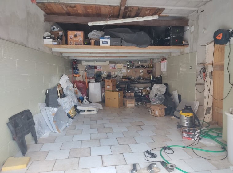 Fondo garage in fase di ristrutturazione con attrezzi, scatoloni e materiali da lavoro, ambiente pratico per progetti di ristrutturazione casa, ambienti in costruzione con strumenti utili per lavori fai-da-te.