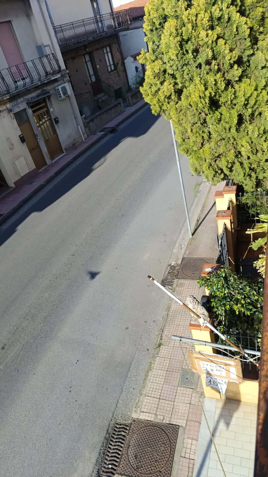 Immagine di una strada urbana tranquilla con alberi e case, con attenzione a una zona residenziale e agli elementi architettonici, ideale per servizi di compravendita e gestione immobiliare NextCasa.