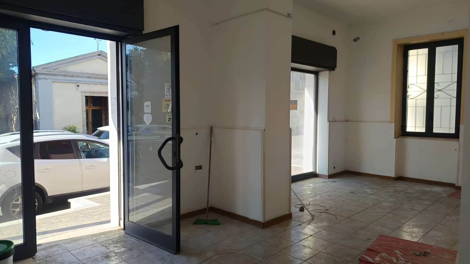 Finestra e porta di ingresso con vista sulla strada, interni di un immobile in fase di ristrutturazione, pareti bianche e pavimento in piastrelle, luce naturale, ambiente pronto per essere arredato.