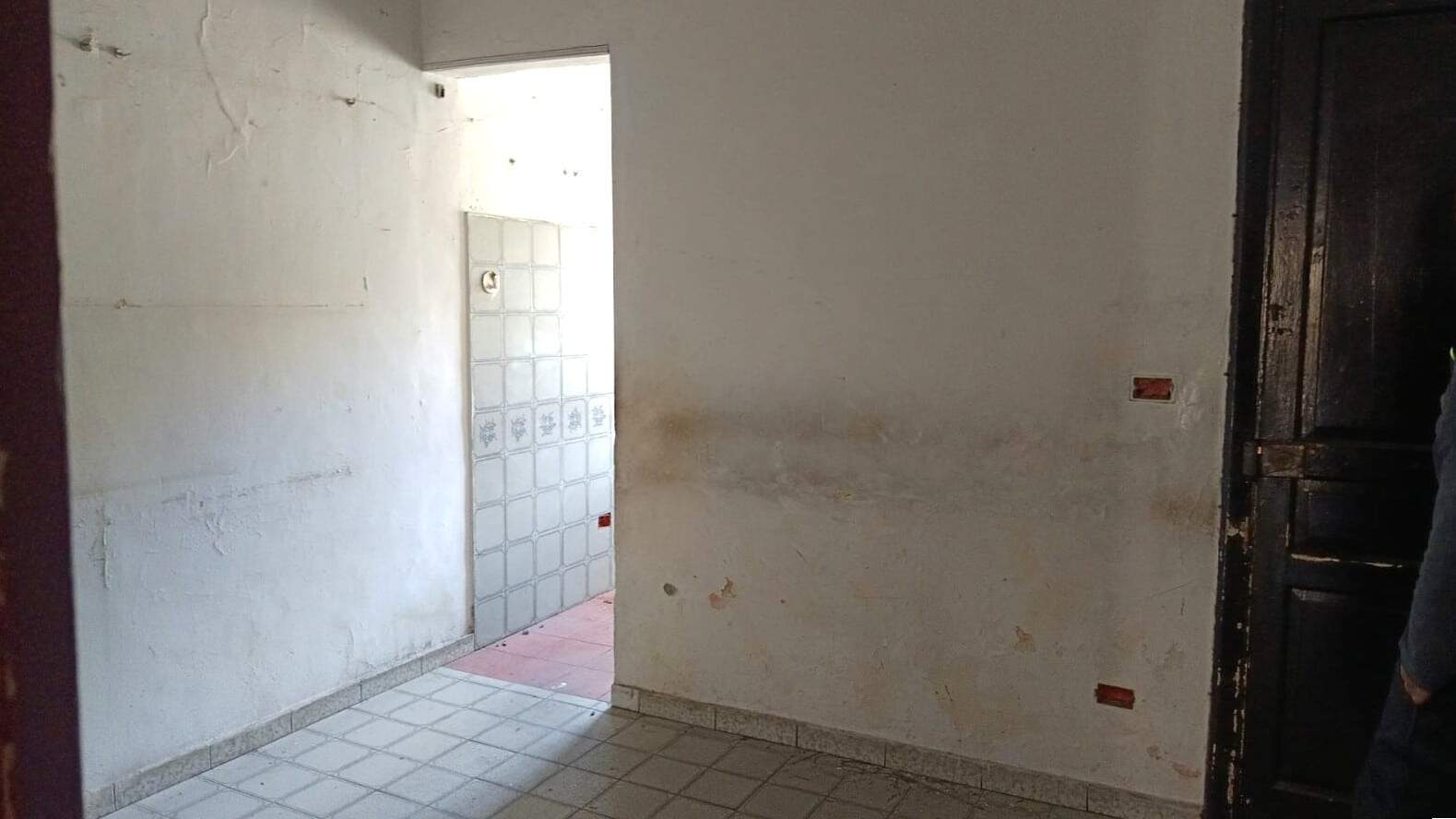 Parete interna di una casa in ristrutturazione con pareti ruvido, pavimento in piastrelle, ingresso e porta di legno scuro, ideale per progetti di upgrade immobiliare.