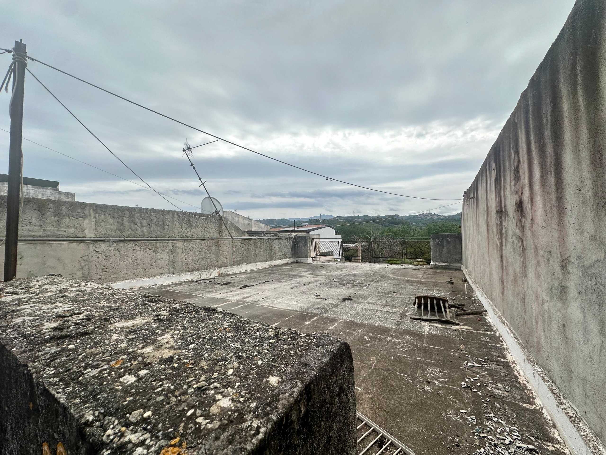 Tetto panoramico di un edificio con viste sulle colline circostanti, struttura in cemento e muri in pietra, ideale per ristrutturazione e progetti di edilizia sostenibile.