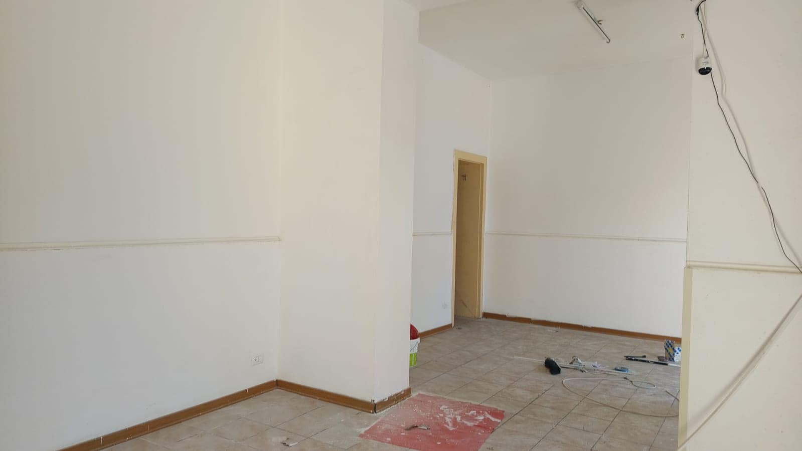 Finiture interne di appartamento in ristrutturazione, pareti bianche e pavimenti in ceramica, lavori di edilizia in corso, ambienti spaziosi e luminosi.