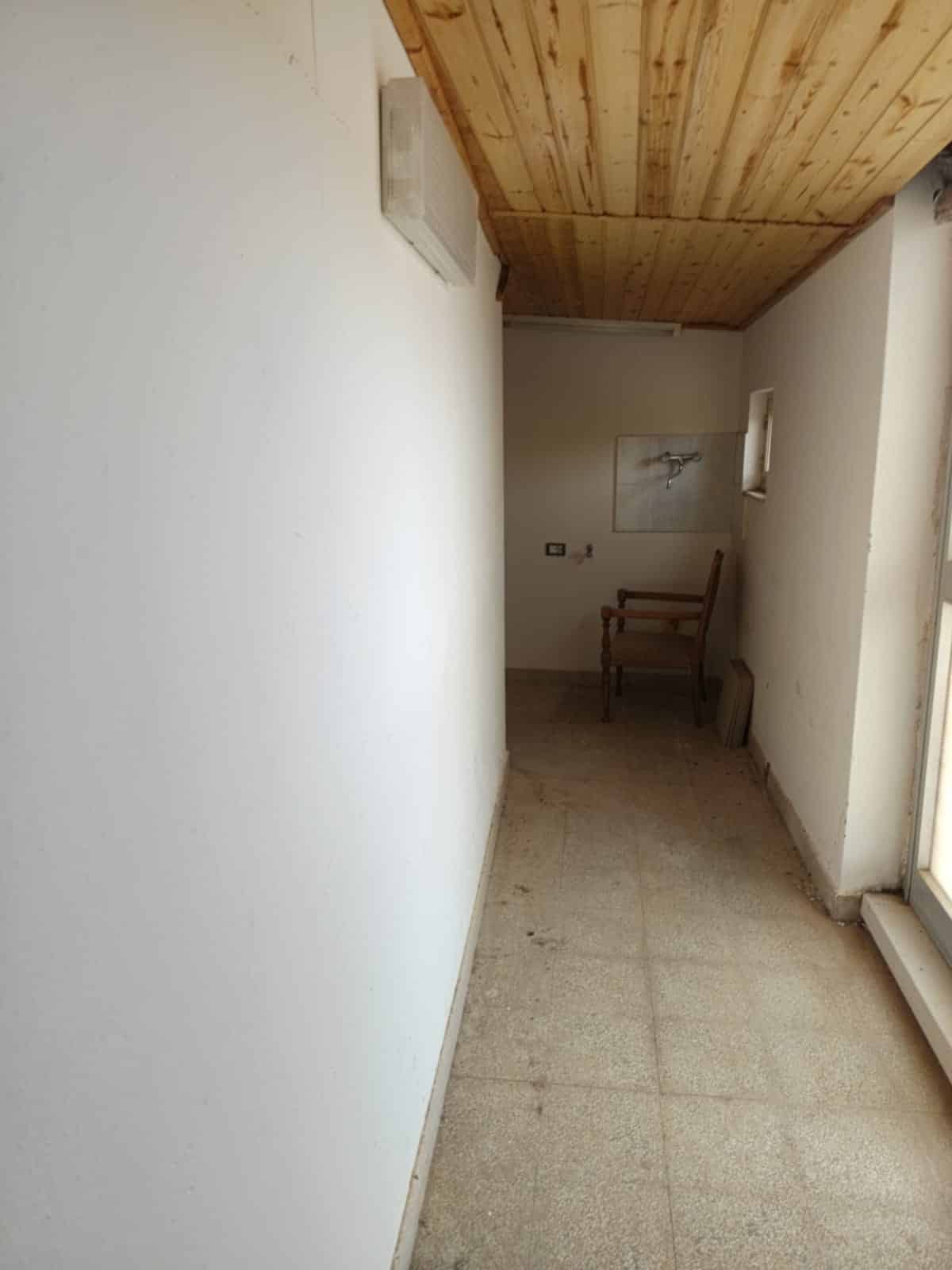 Sgombero ufficio con pareti bianche, pavimento in piastrelle e soffitto in legno, pronto per ristrutturazione o arredo.