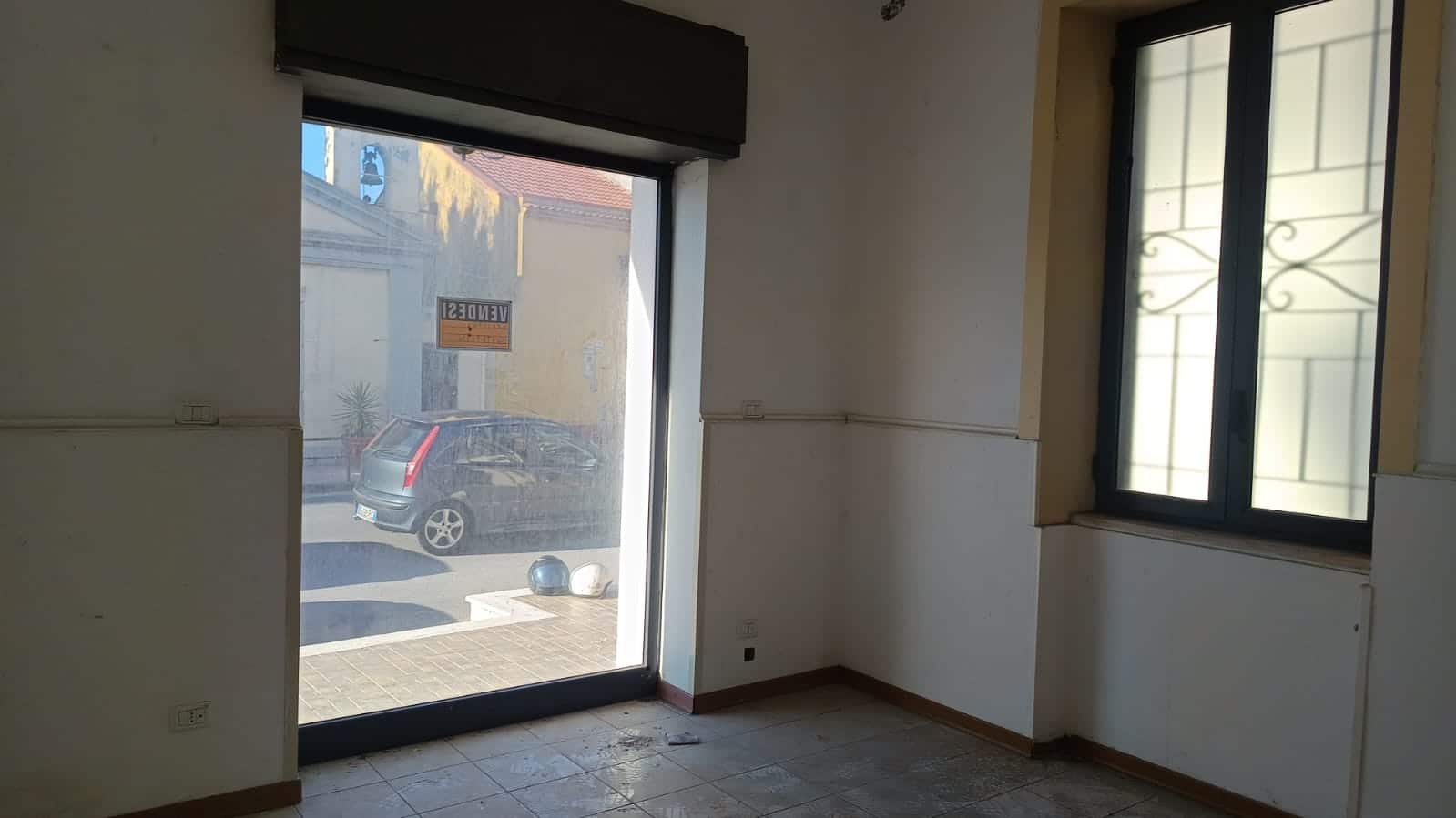 Finestra e porta in vetro con vista sulla strada e interno di un appartamento ristrutturato, luminoso e pronto per essere arredato, ideale per investimento o prima casa.