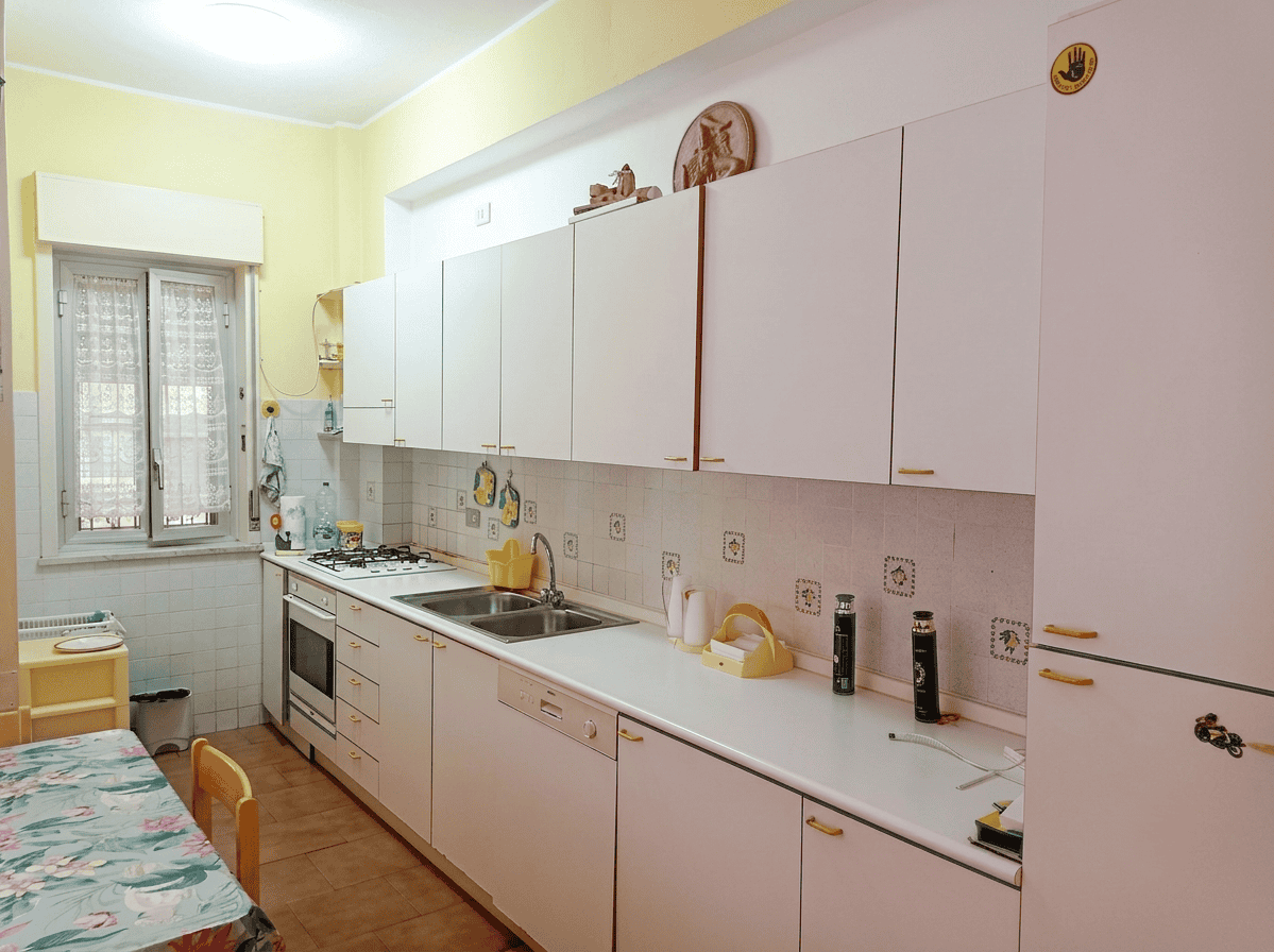 Cucina luminosa e moderna in un appartamento a Oliveri, con mobili bianchi, piano di lavoro spazioso e elettrodomestici inclusi.