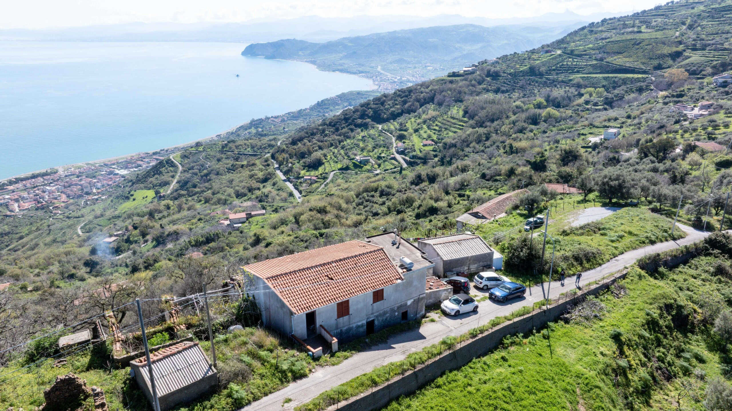 Vista aerea di una casa in collina con vista sul mare e paesaggi rurali, ideale per investimento immobiliare e residenziale in zona tranquilla e panoramica in Italia.