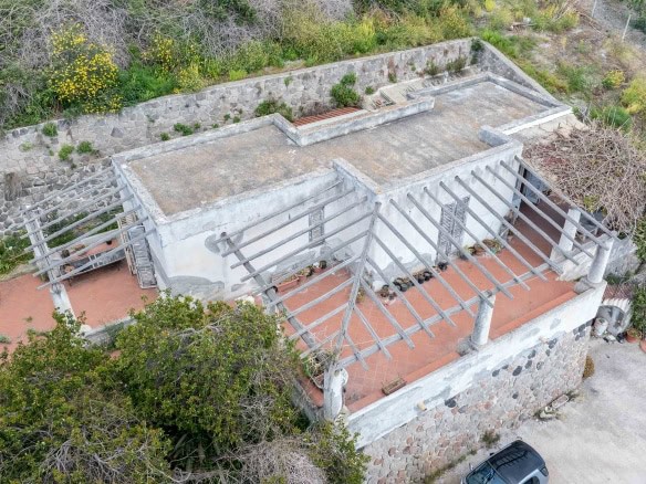 Casa rustica in pietra con terrazza e pergolato in legno, immersa nel verde, ideale per relax e vita all'aperto, proprietà esclusiva in zona panoramica.
