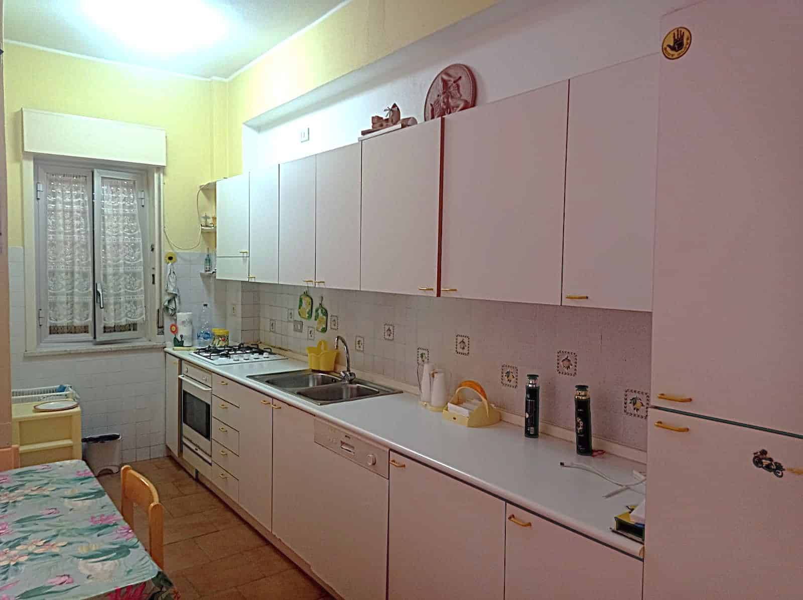 Cucina moderna con mobili bianchi, piano di lavoro e accessori in casa, arredamento funzionale, ideale per abitazioni accoglienti e pratiche.