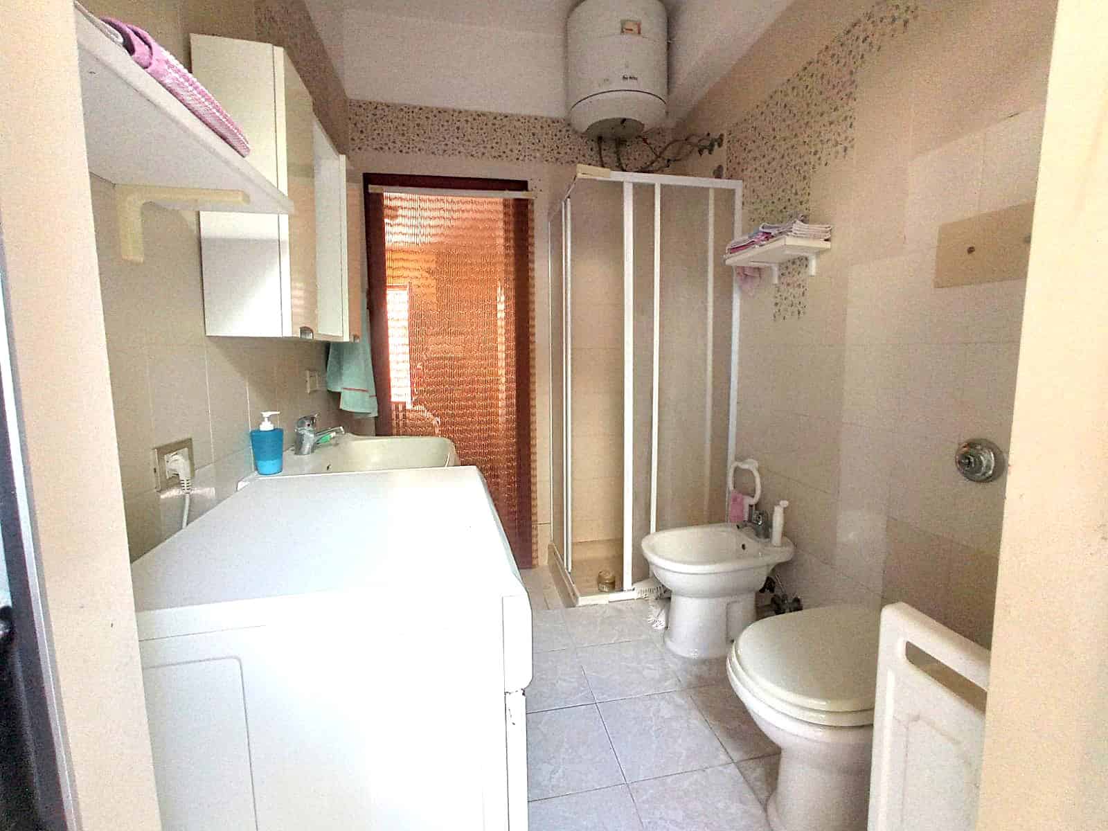 Lavabo, bidet e servizi igienici in un bagno di casa, con dettagli pratici e funzionali, spazio per lavatrice e asciugatrice, ideale per appartamenti e case di città, in un contesto di vita quotidiana.