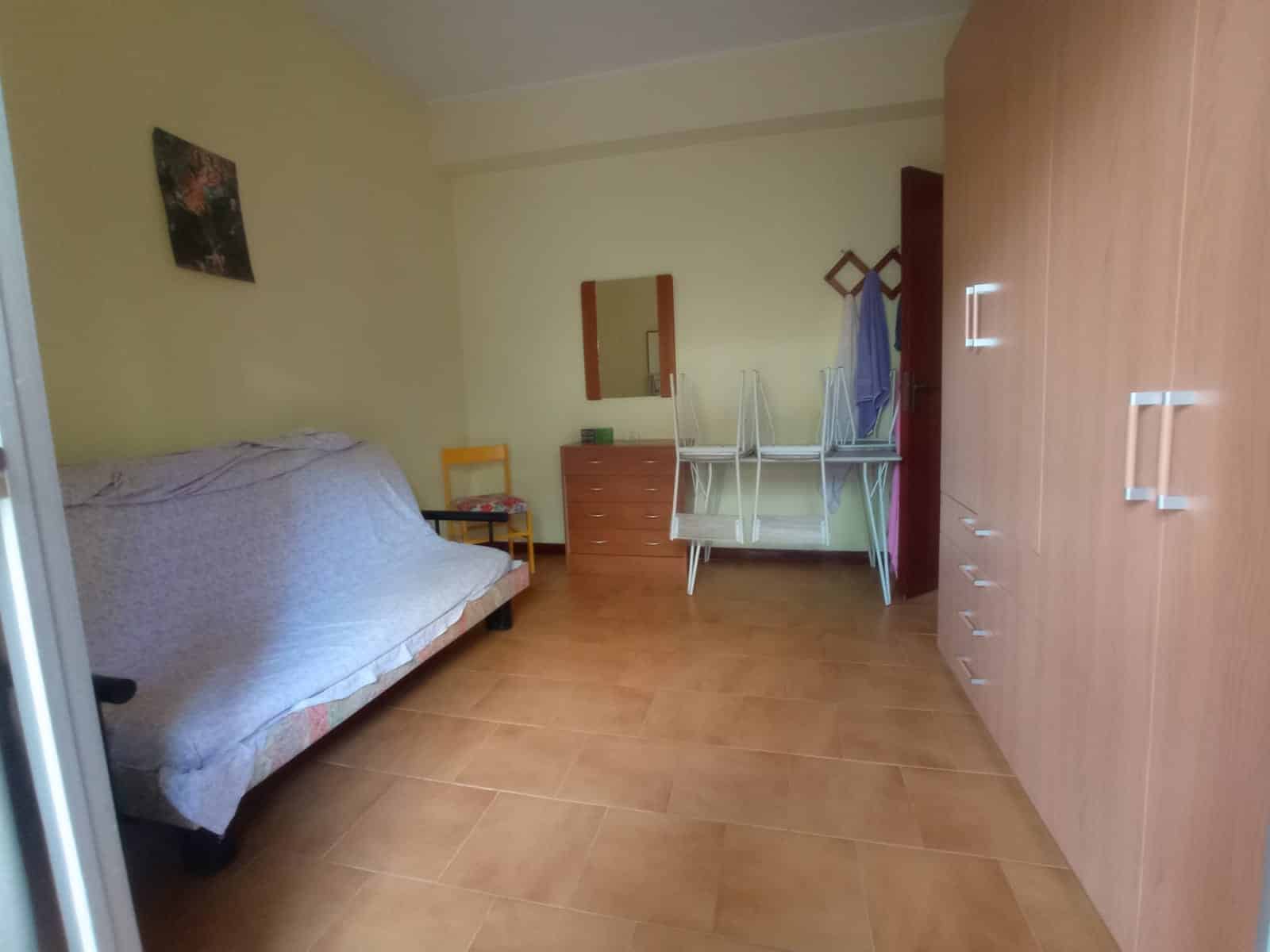 Camera da letto con arredi funzionali e armadio in stile moderno, ideale per case in affitto o soggiorni temporanei, con colori caldi e armadio capiente.