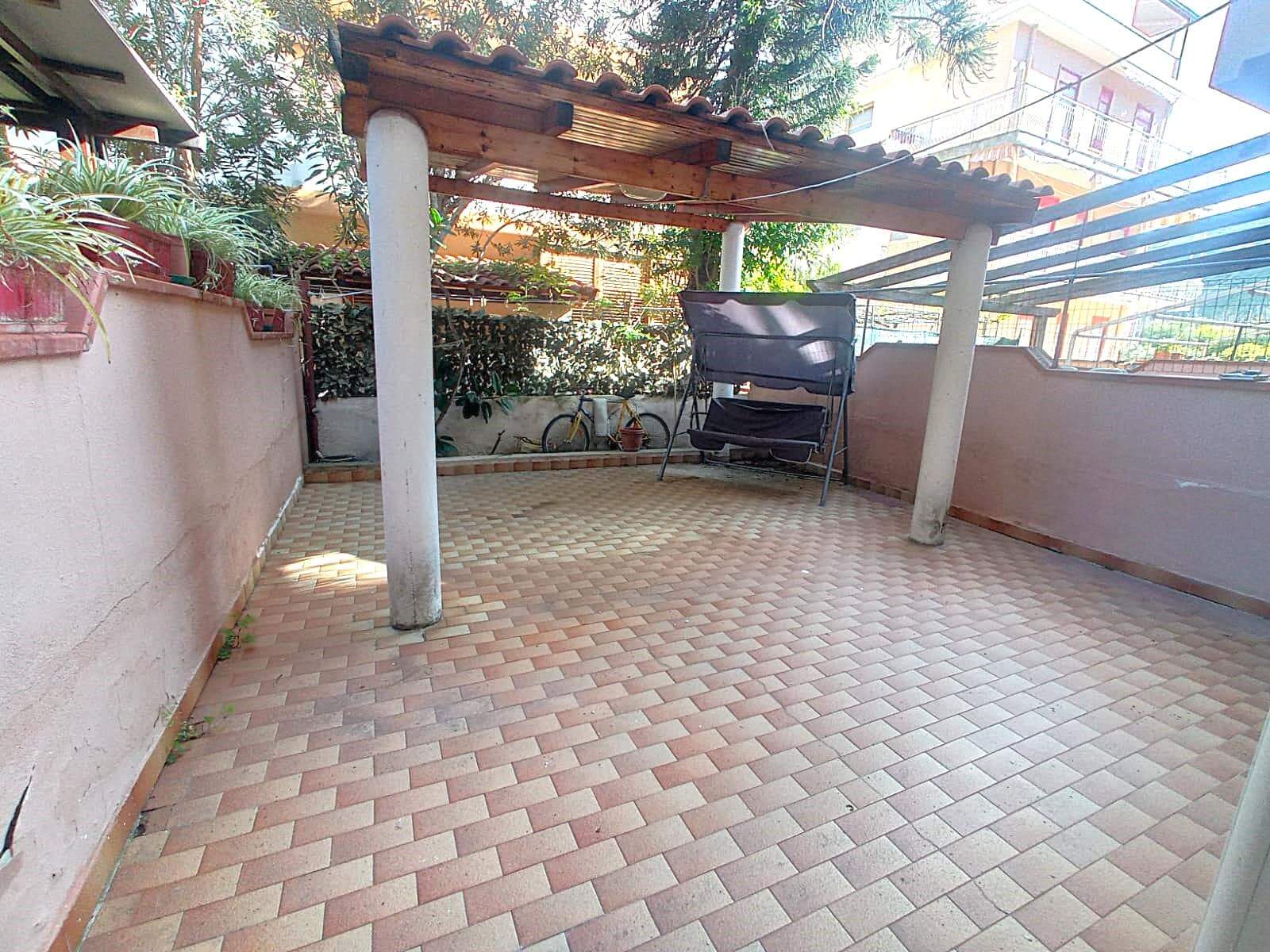 Relaxing terrace with tiled floor, wooden pergola, and potted plants, ideal for outdoor living and entertaining in a private residential setting.