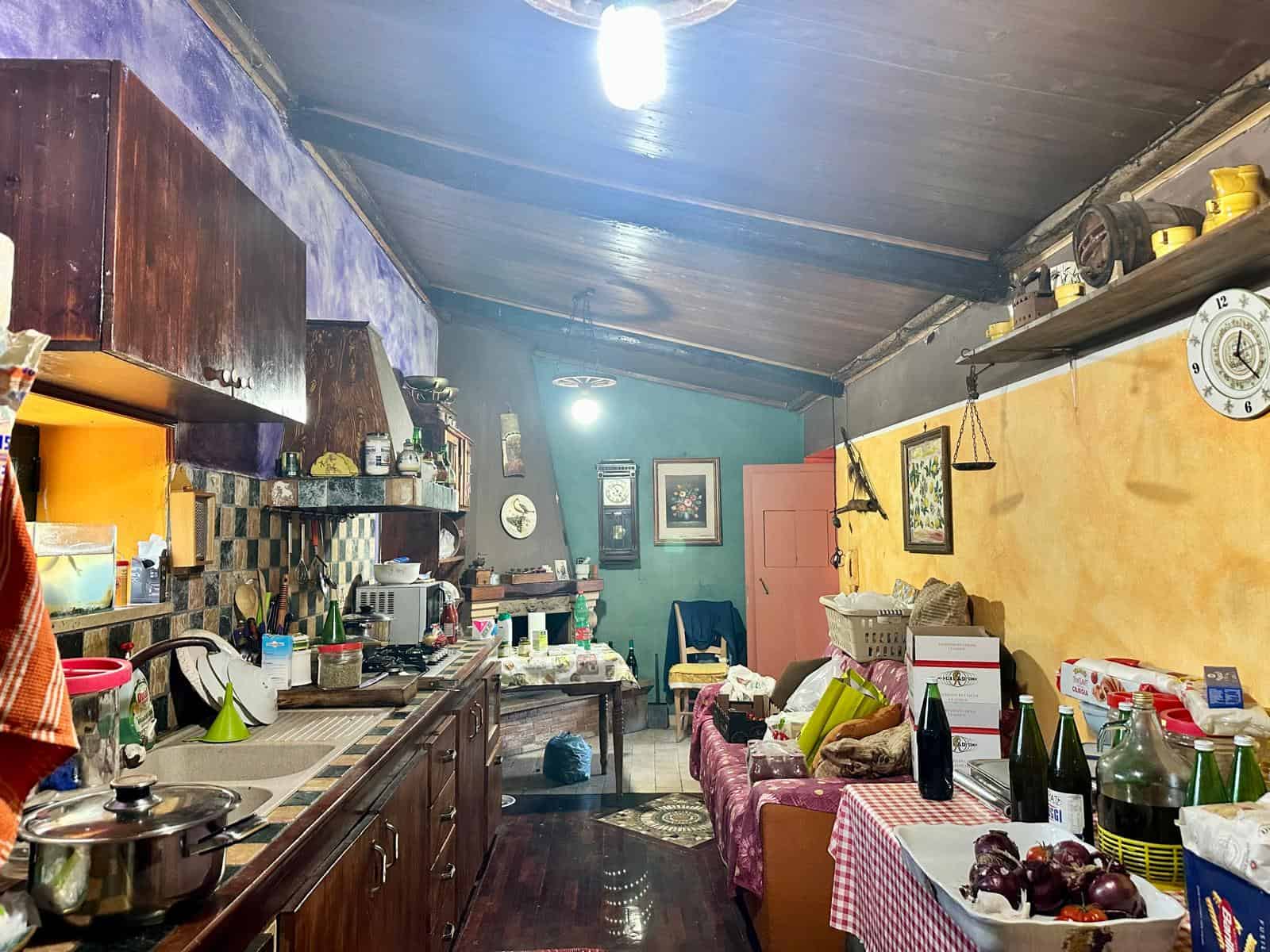 Rustico cucina in stile tradizionale con mobili in legno, pareti colorate, stoviglie e utensili vari, ambiente accogliente e informale ideale per convivialità e cucinare con passione.