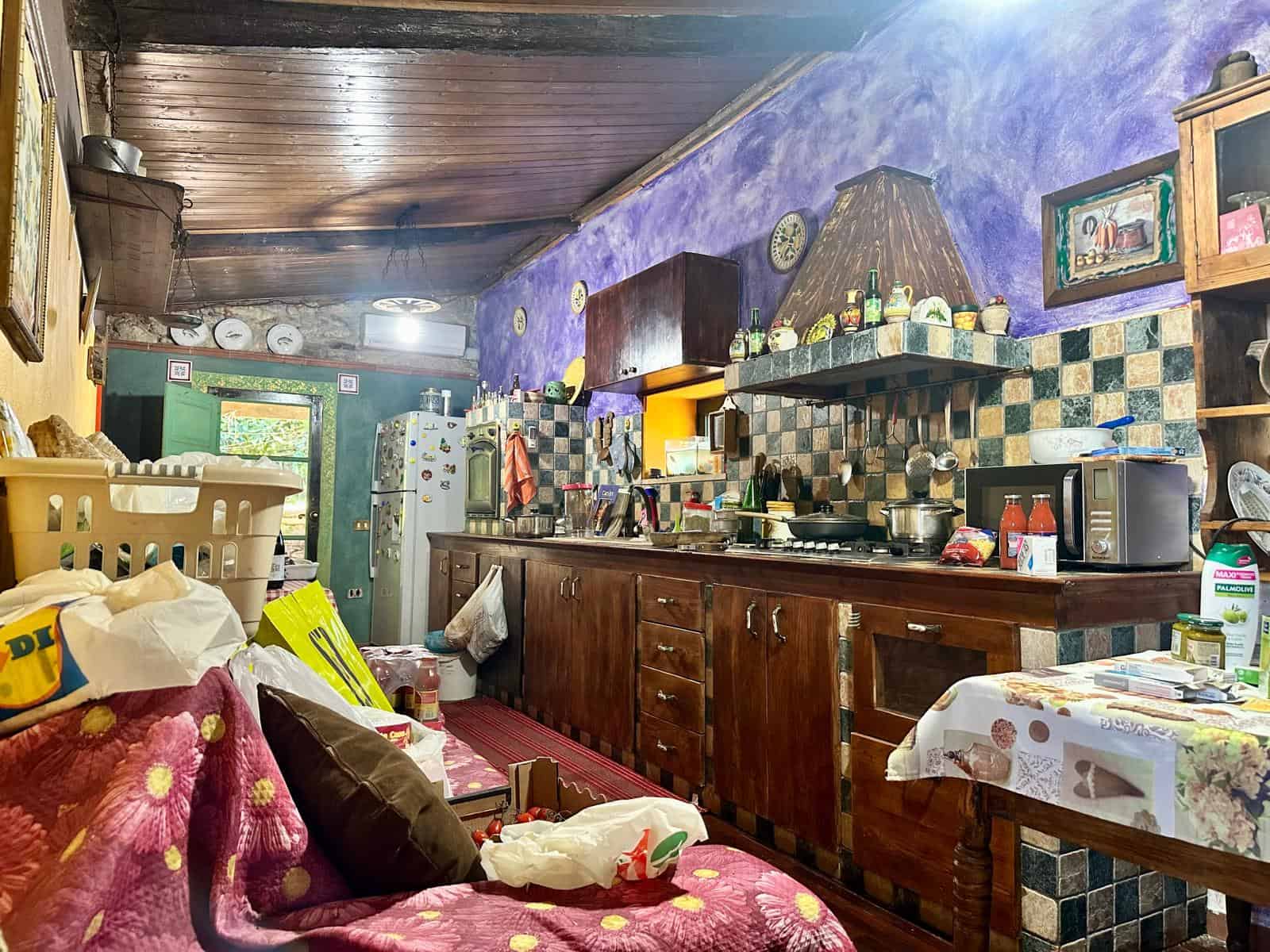Casetta rustica con cucina in muratura, arredi in legno, pareti colorate e stile accogliente, ideale per soggiorni in famiglia o weekend immersi nella natura.\nOttima soluzione di residence rustico.