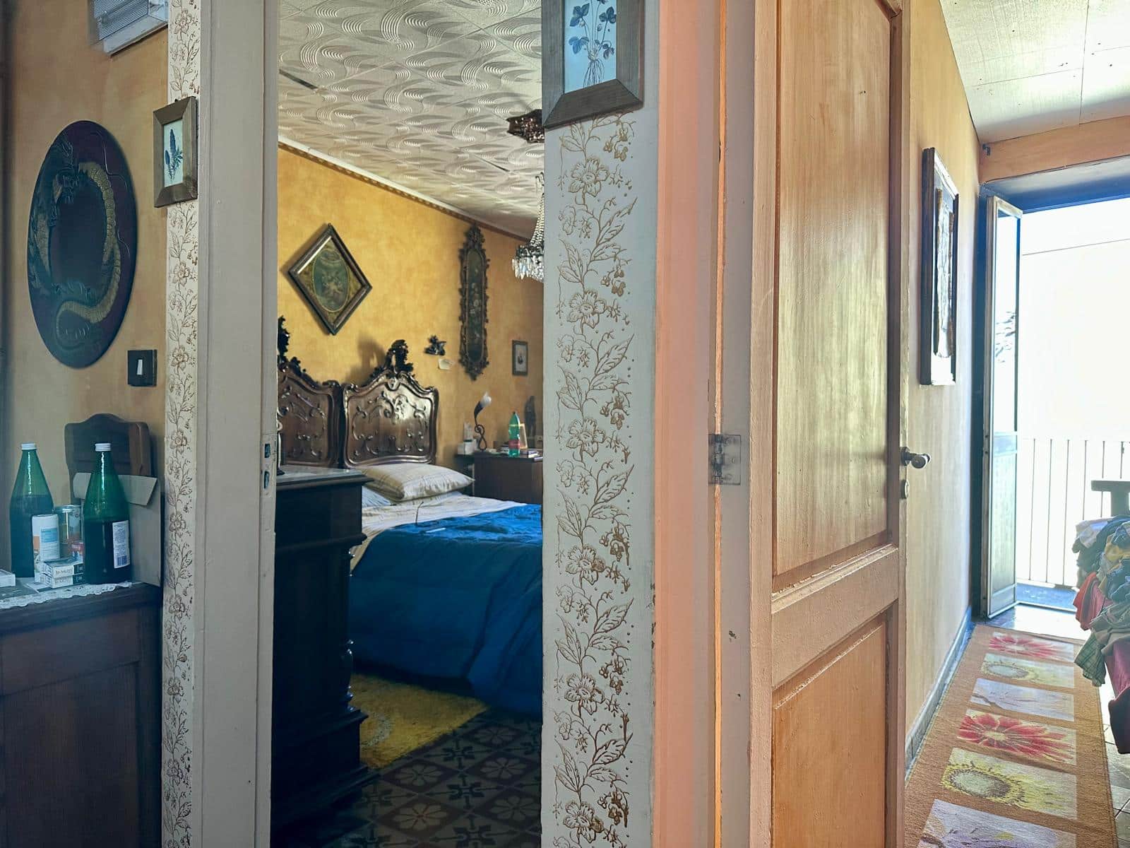 Vecchia casa in stile vintage con camera da letto decorata con mobili eleganti e dettagli d'epoca, ingresso con porta e balcone che permette di ammirare la vista all'aperto.