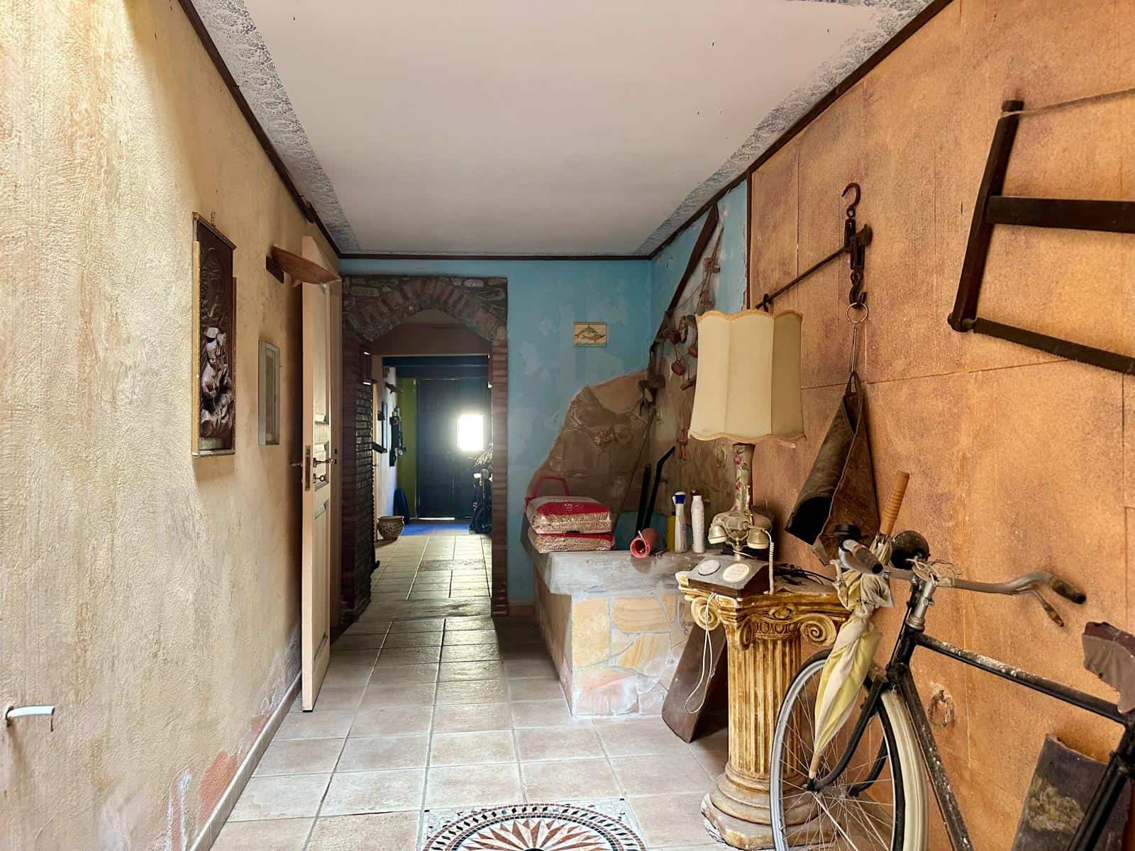 Vita in stile rustico con pareti colorate, arredi vintage, lampada d'epoca, bicicletta e dettagli decorativi che creano un'atmosfera accogliente e autentica. Perfetto esempio di arredamento casa tradizionale italiana.