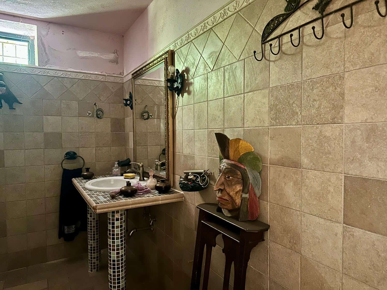 Lavandino bagno con mosaico, specchio antico e decorazioni artigianali in stile rustico, ambientazione vintage e retrò, dettagli di arredo e arredi originali, spazio accogliente ed elegante.