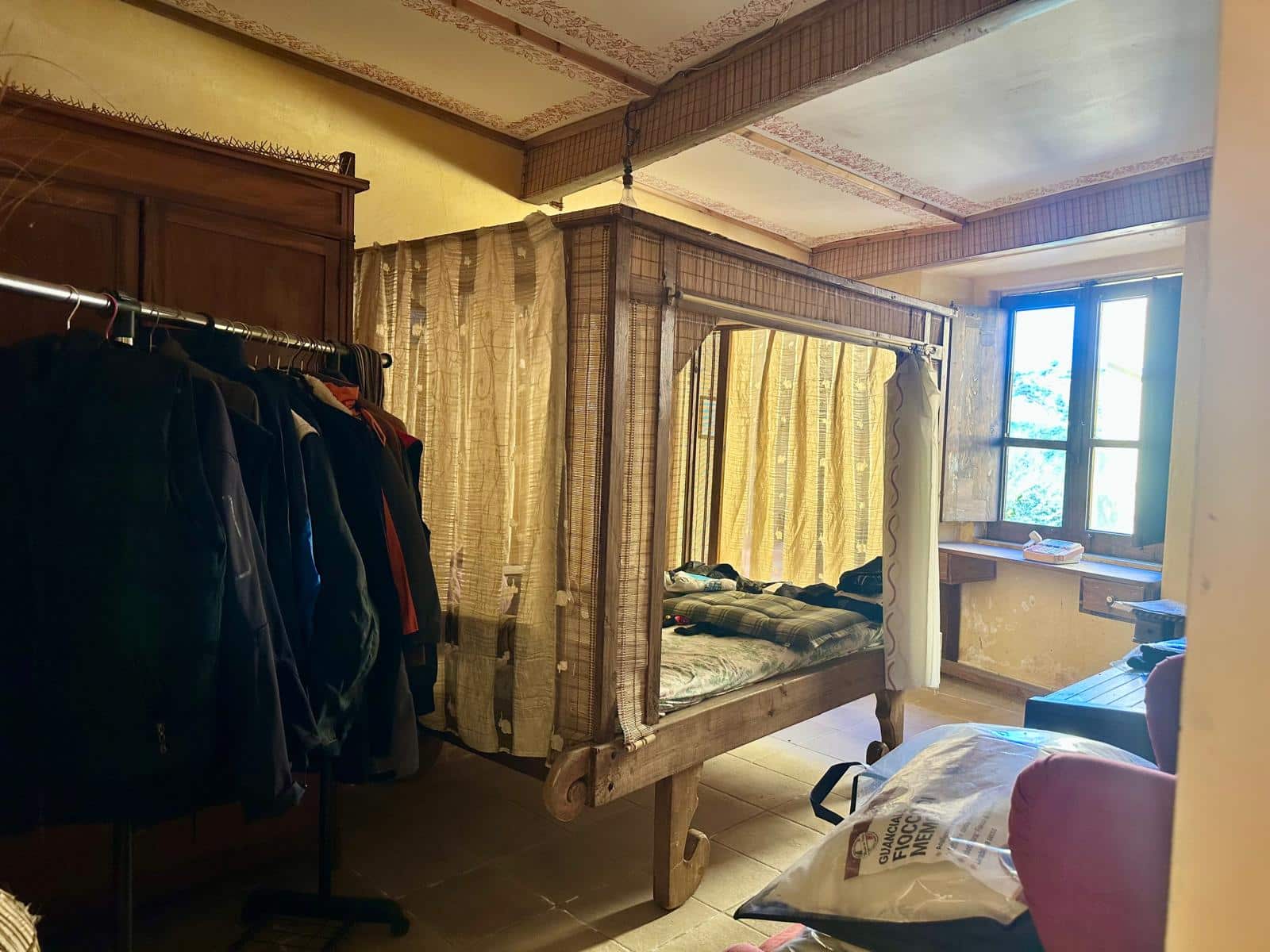 Vecchia camera da letto con lettino, armadio e finestra, ambiente abitabile e con arredi tradizionali, possibile ristrutturazione casa.