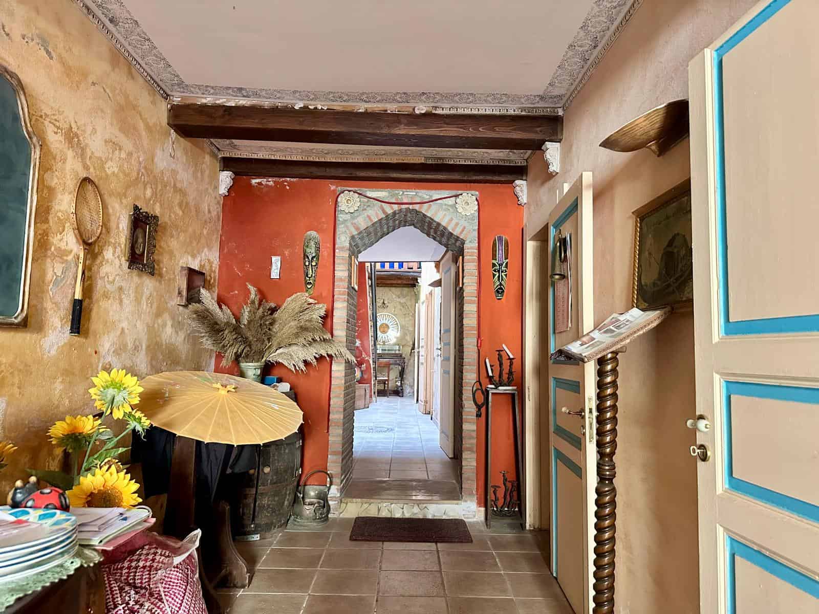 Colorato ingresso rustico con pareti decorate, oggetti d'antiquariato e dettagli in stile etnico, caratterizzato da un mix di stile boho e mediterraneo, ideale per case dal charme vintage e atmosfera accogliente.