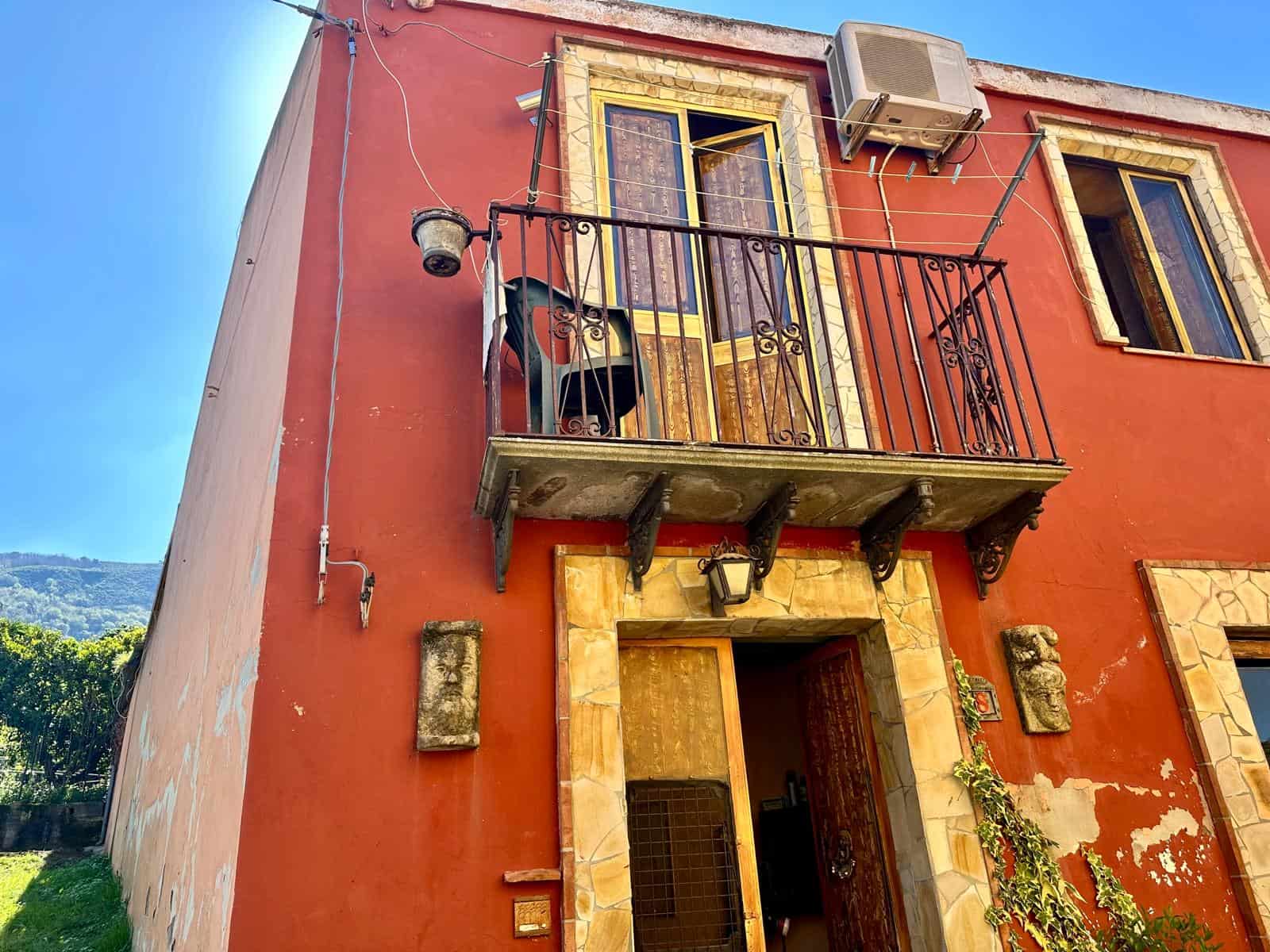 Balcone con ringhiera in ferro battuto e aria condizionata, facciata di casa in stile rustico con dettagli in pietra, ambientazioni di proprietà NextCasa, immobiliare specializzata in case di charme in Italia.