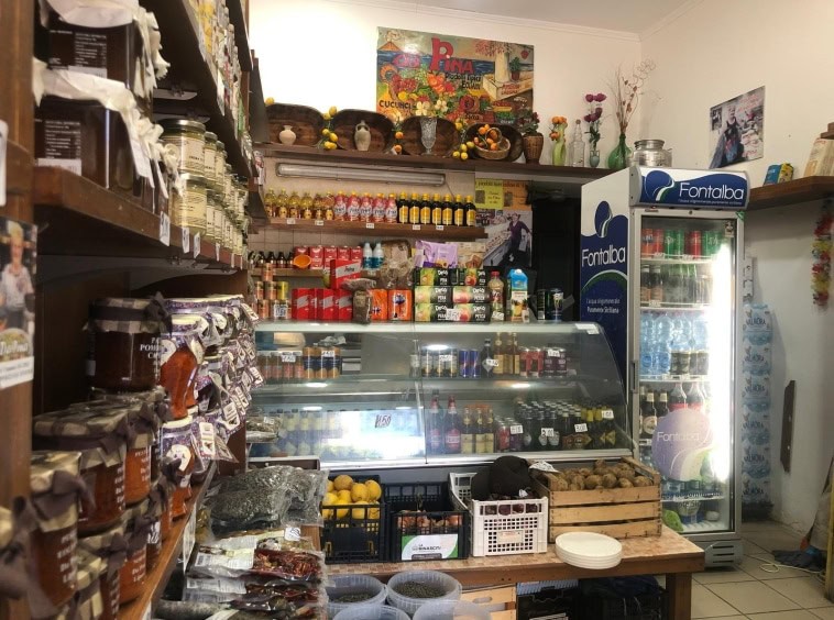 Panevozze di alimentari e prodotti tipici in un negozio di generi alimentari a NextCasa, con frigorifero e scaffali pieni di conserve, spezie, snack e prodotti freschi, un angolo accogliente e ben fornito.