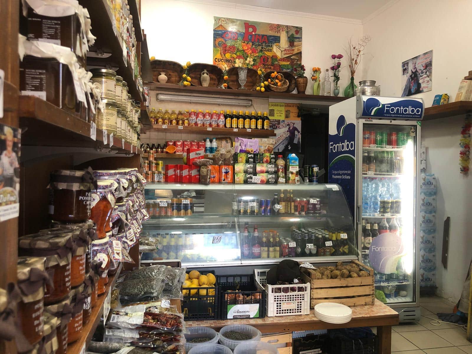 Panevozze di alimentari e prodotti tipici in un negozio di generi alimentari a NextCasa, con frigorifero e scaffali pieni di conserve, spezie, snack e prodotti freschi, un angolo accogliente e ben fornito.