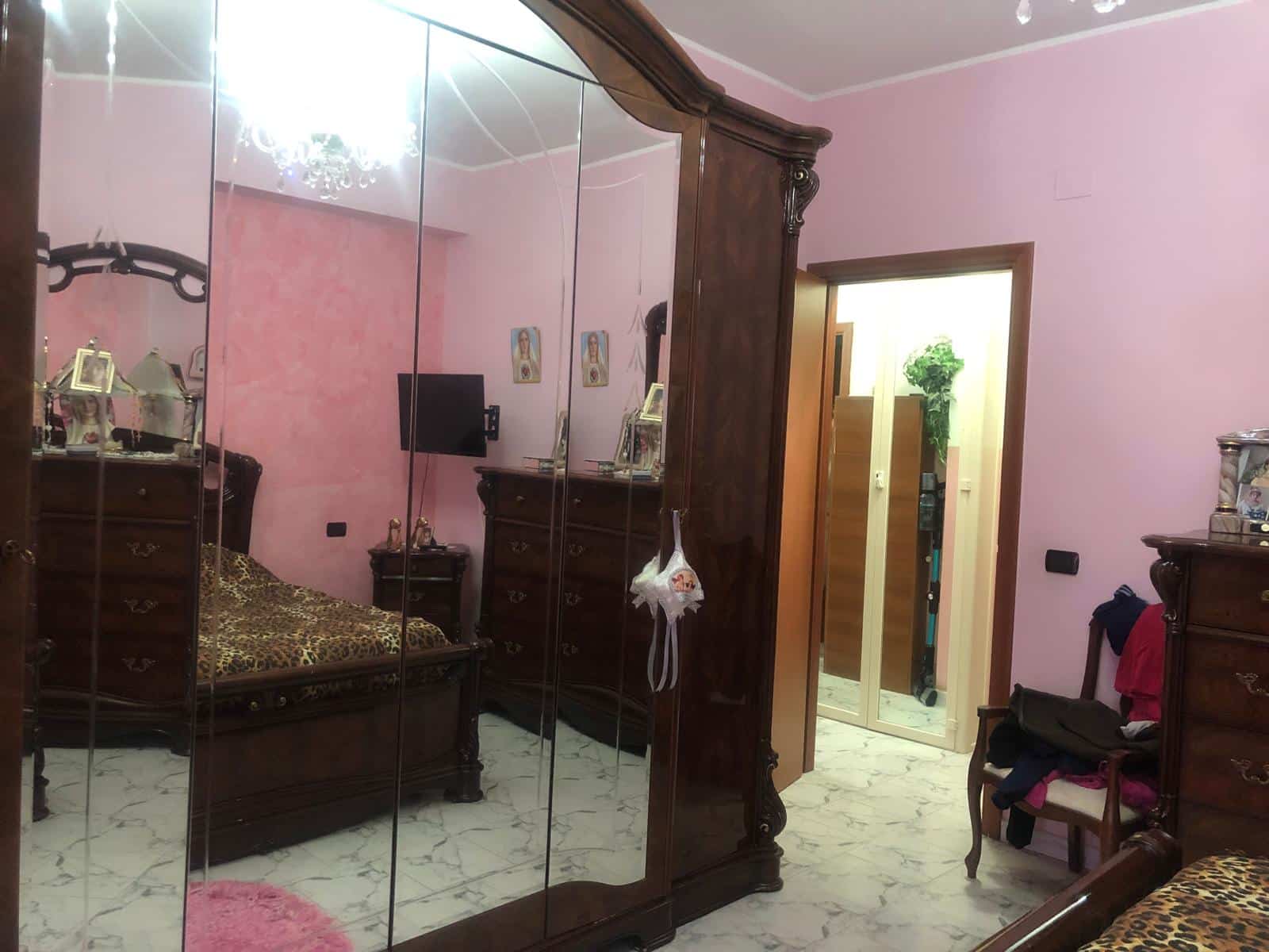 Armadio antico in legno massiccio con specchi, camera da letto con panna e rosa, mobili classici e letto con testiera in stile barocco.