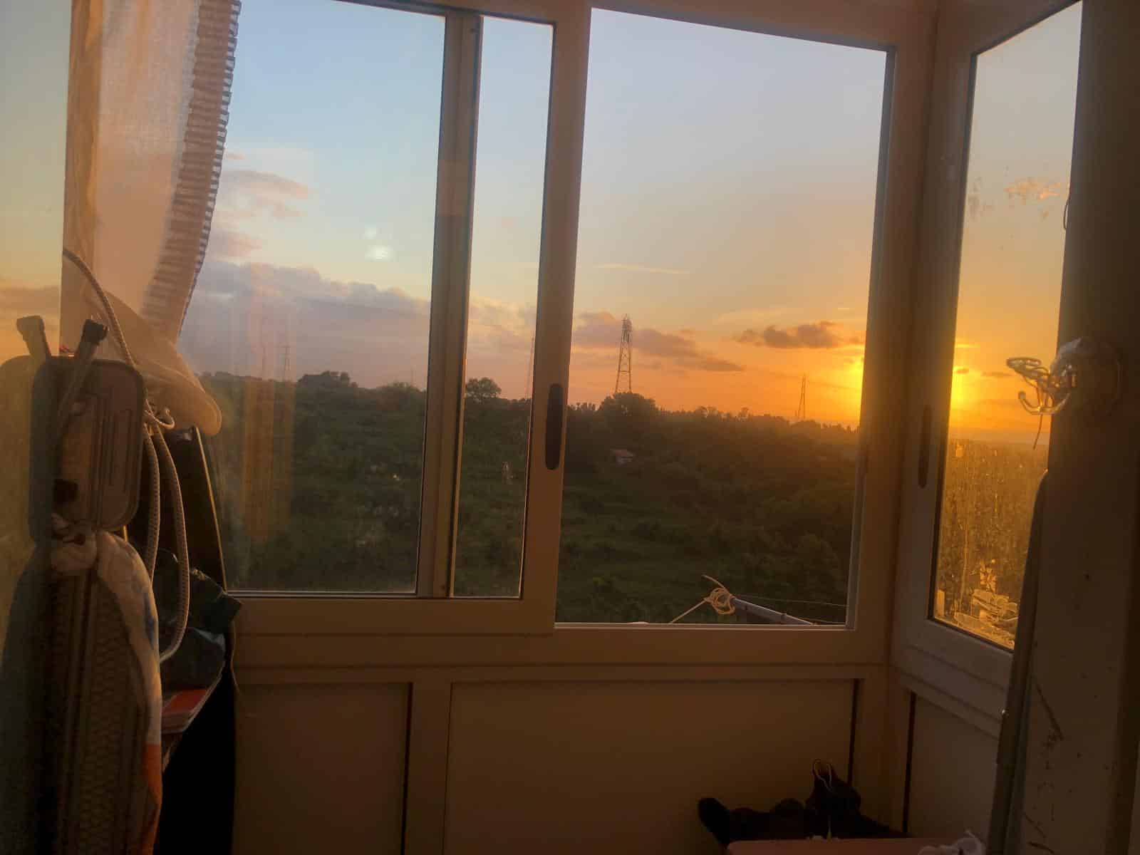 Finestra con vista sul tramonto, paesaggio naturale, casa moderna, terapia visiva, ambiente di soggiorno, vista panoramica, illuminazione calda, luce naturale, comfort domestico, immobile in vendita.