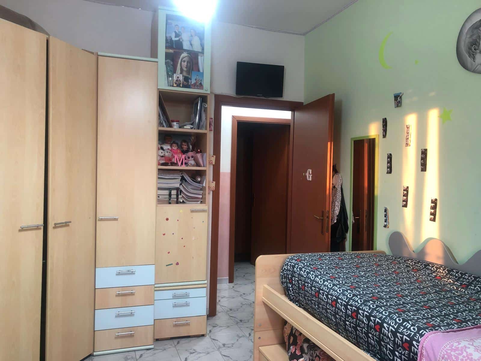 Letto singolo con armadio in camera da letto, parete verde chiaro, decorazioni con foto e luna, ambiente accogliente e pratico, soluzione ideale per camere studenti o bambini, spazio ottimizzato per il riposo e lo svago.