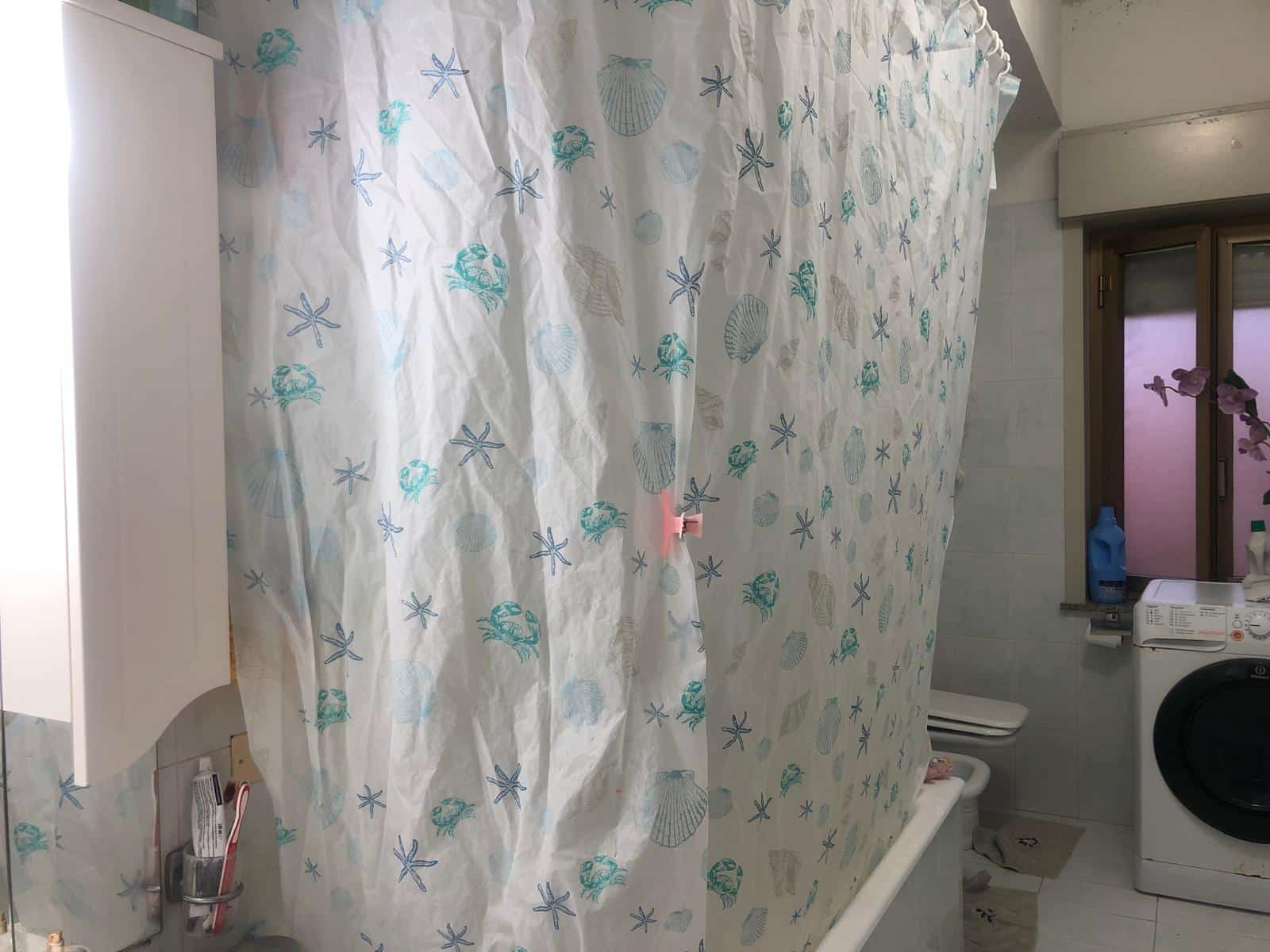 Passeggiata di doccia con tende a tema mare e conchiglie, ideale per ambienti di stile nautico e marino, spazio funzionale e decorativo per il bagno.