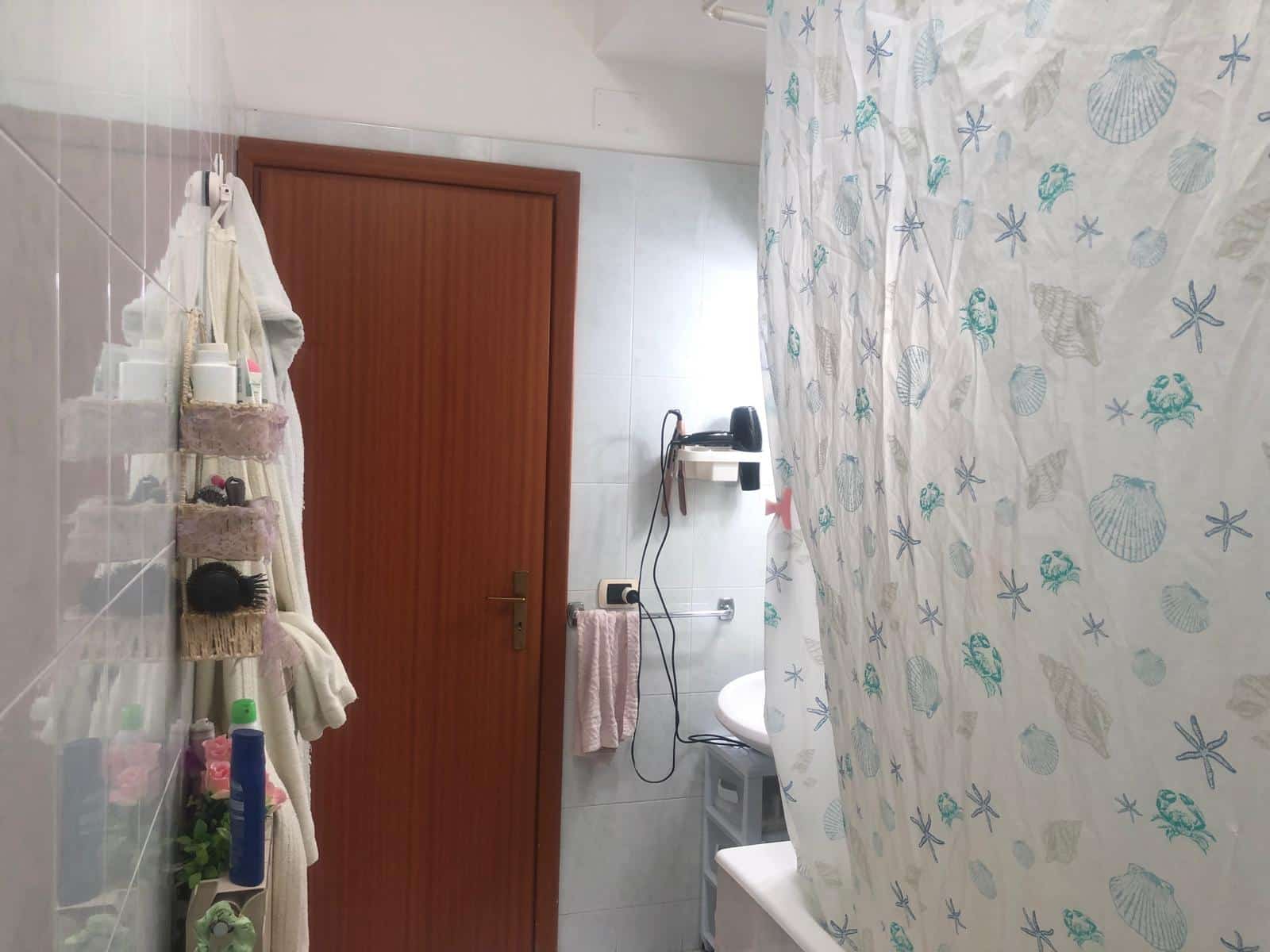 Lavabo con vari prodotti di bellezza e asciugamani in plastica rosa in una stanza da bagno.