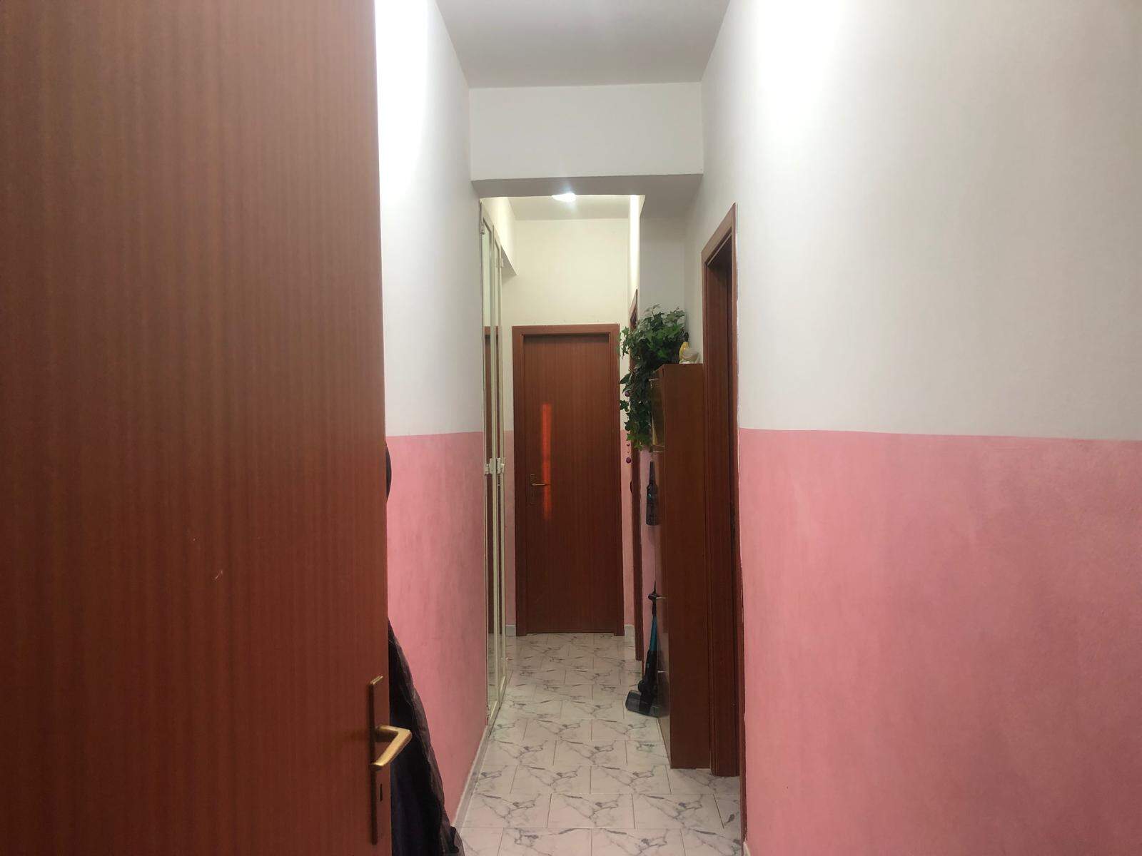 Porte d'ingresso in appartamento con pareti rosa e bianco, pavimento in ceramica, arredamento funzionale e decorativo, ideale per annunci immobiliari e interior design in Italia.