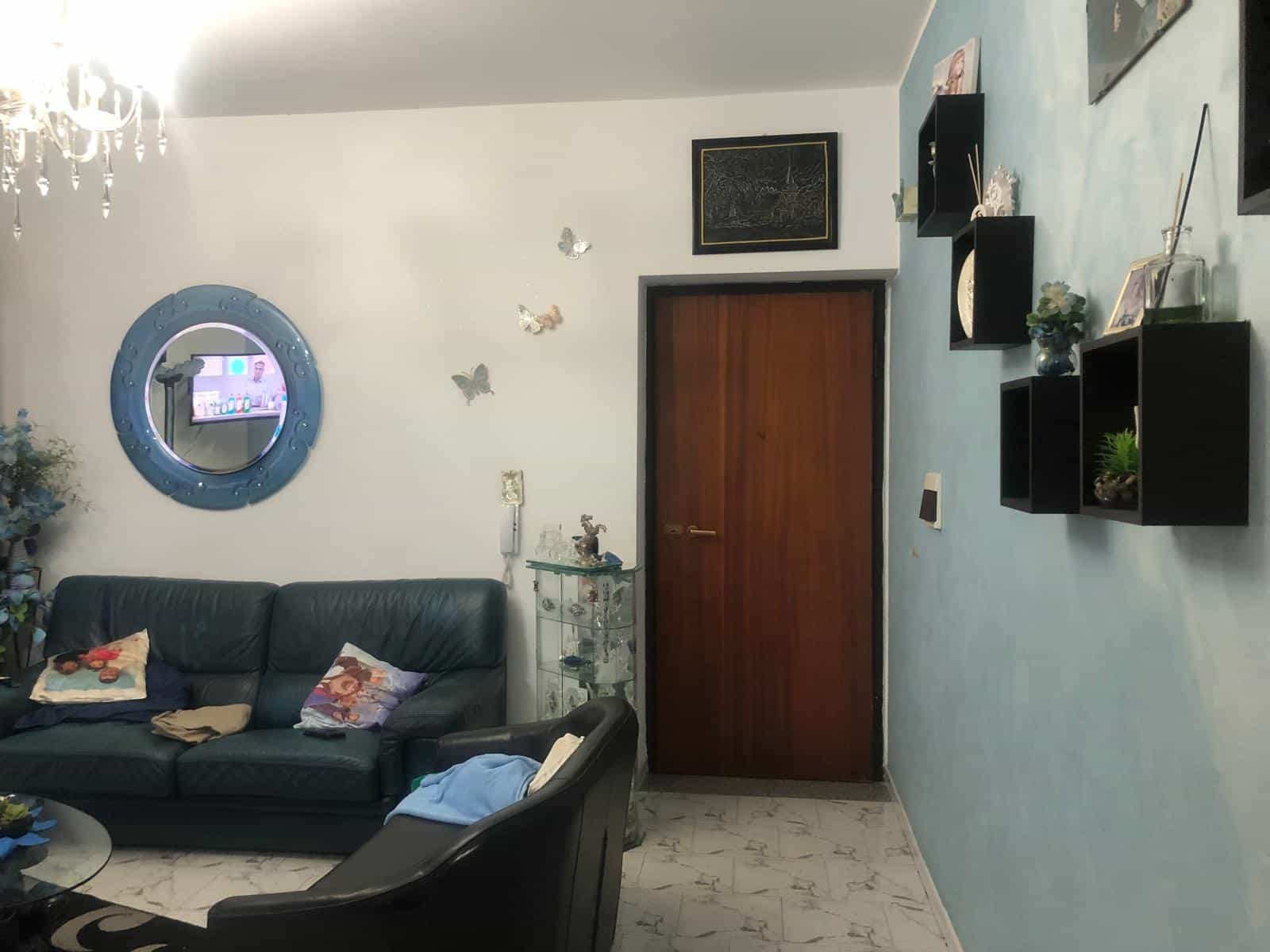 Mobili soggiorno con divano in pelle nera, decorazioni floreali e a farfalla, pareti colorate, pareti con mensole nere, cornice moderna, spazio accogliente e arredamento elegante.