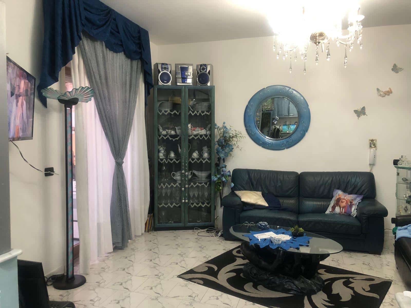 Motivo di un soggiorno con divano nero, camino centrale e dettagli decorativi eleganti; atmosfera calda e accogliente, perfetta per vivere momenti di relax in casa.