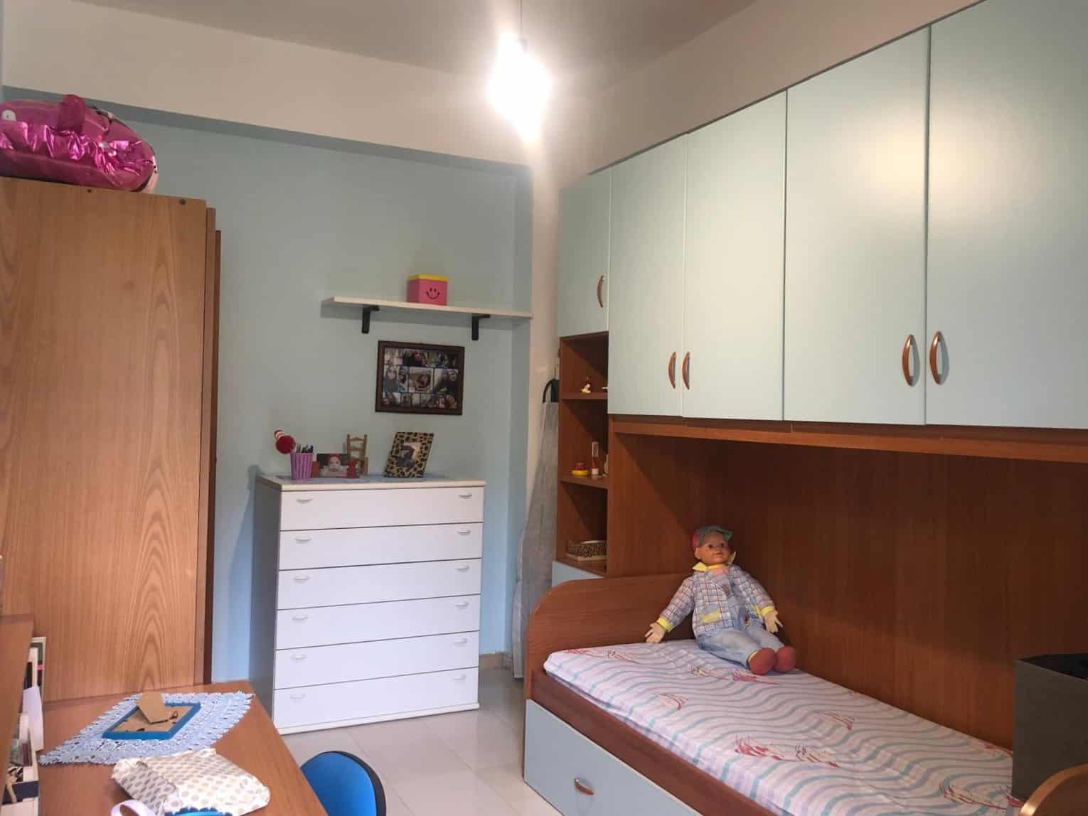 Letto singolo con armadi a muro in camera per bambini, arredamento funzionale e pratico, decorazione colorata, ideale per ambienti di case e appartamenti, soluzione salvaspazio.